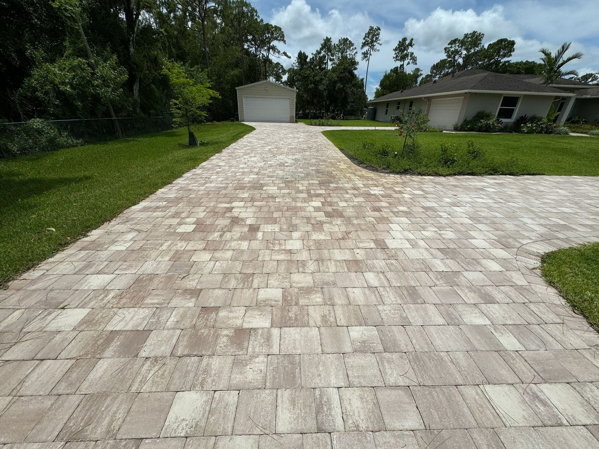 A brick driveway leading to a house with a garage