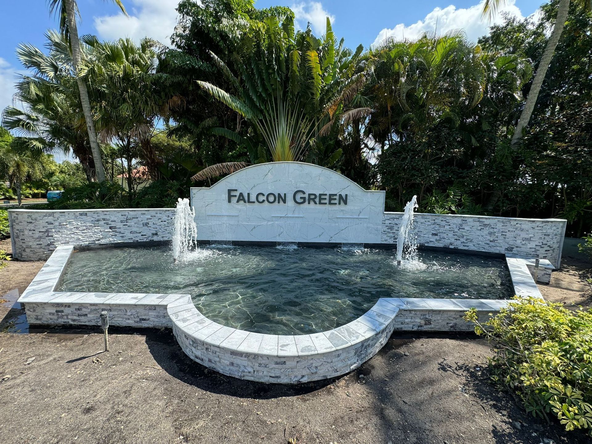 A fountain in front of a sign that says falcon green