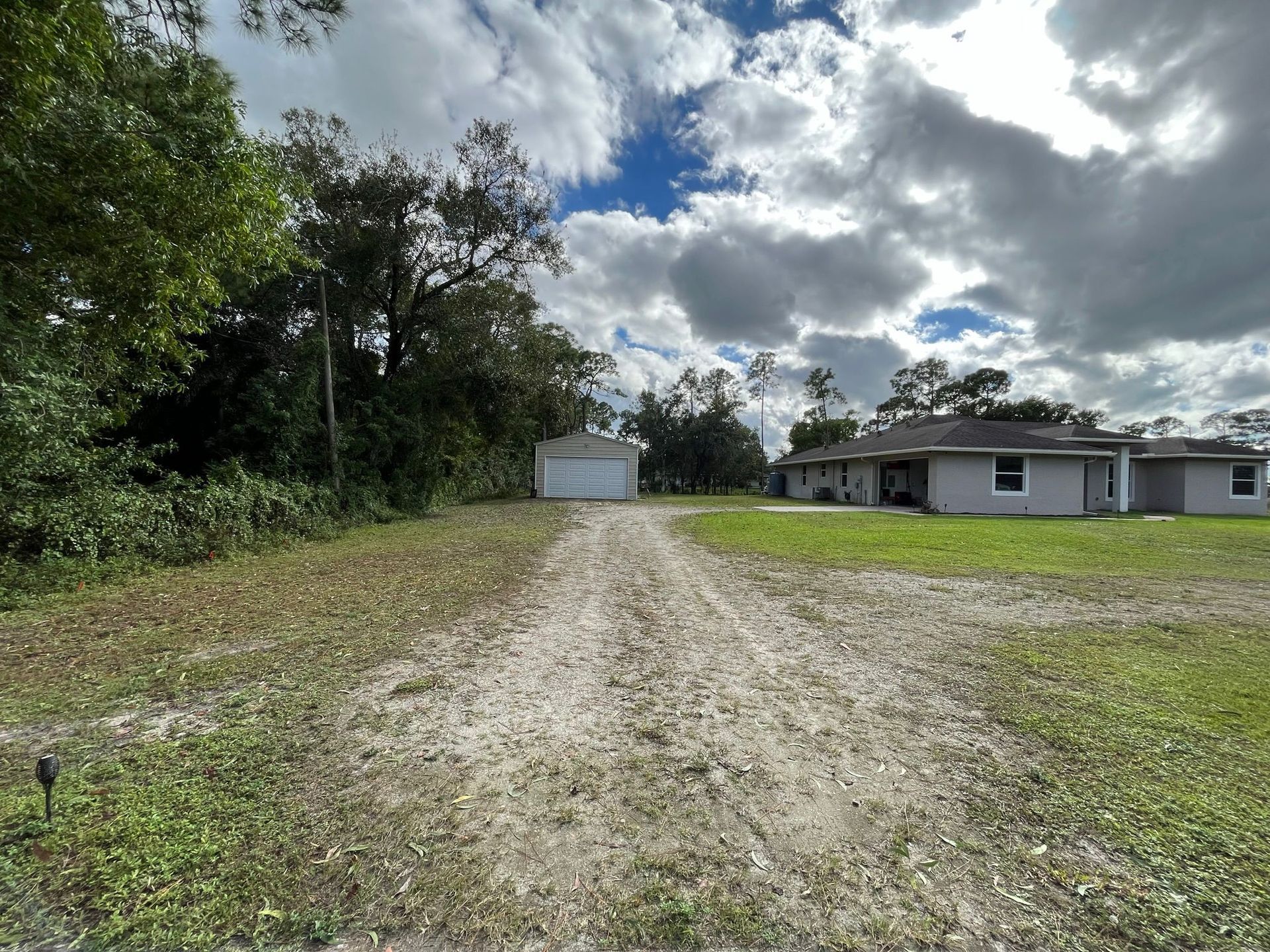 A dirt road leading to a house with a garage