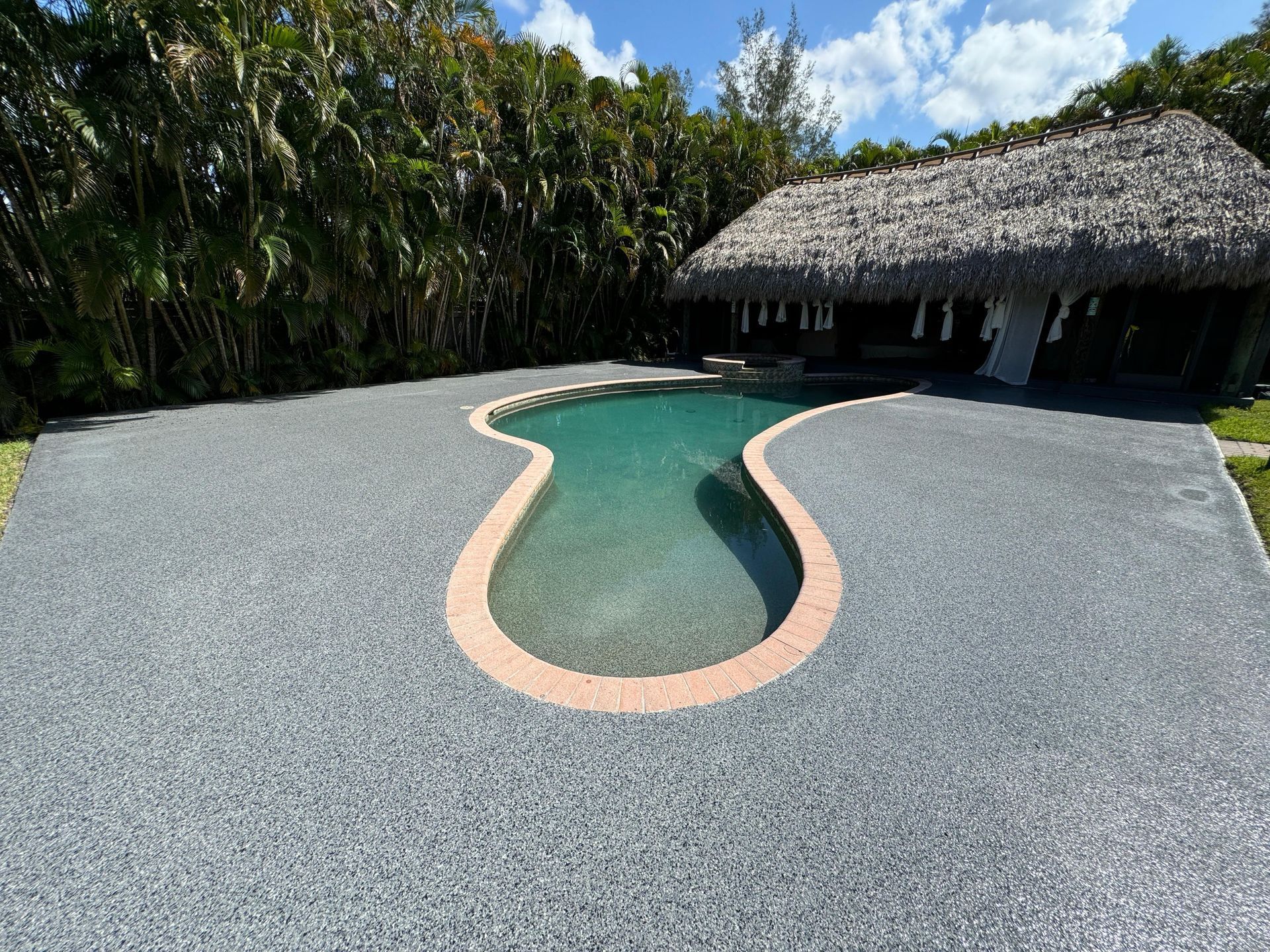 A large swimming pool with a thatched roof in the background