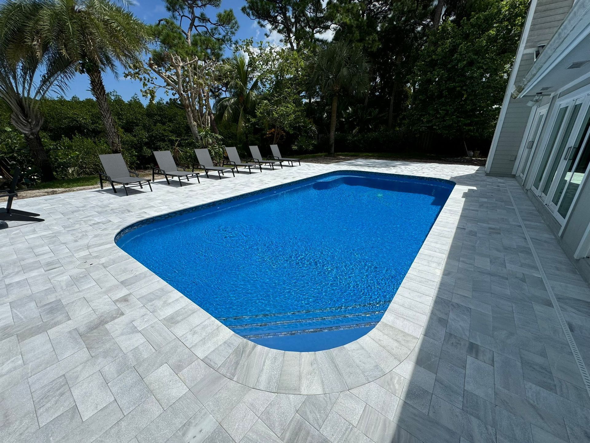 A large swimming pool surrounded by chairs andtrees