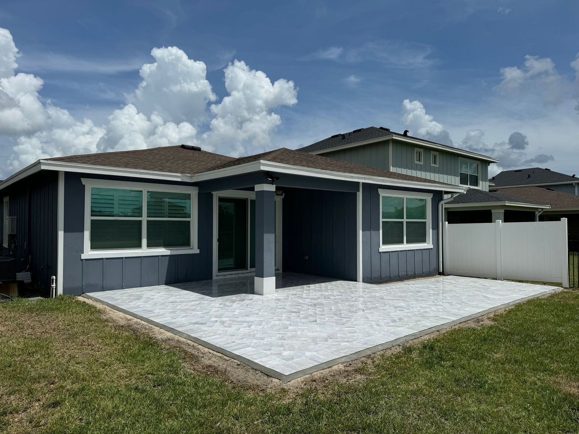 A blue house with a white fence and a patio in front of it