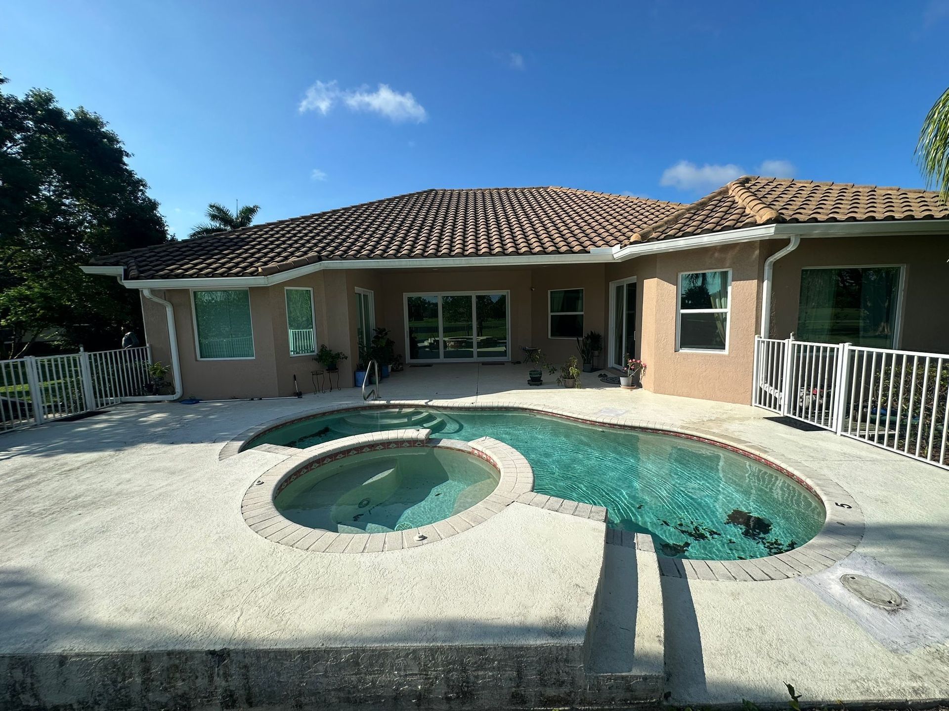 A house with a swimming pool and a hot tub in front of it