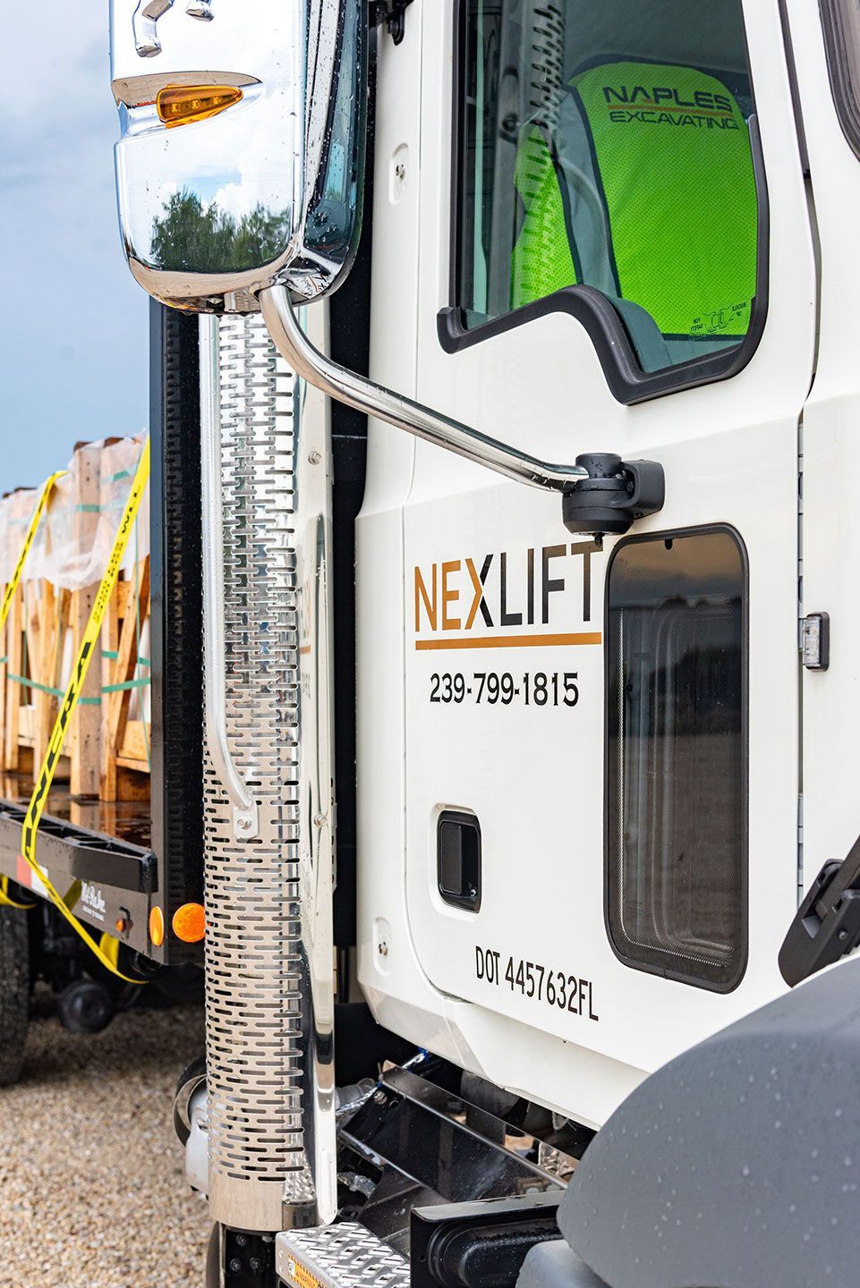 White Nexlift truck with mirror, exhaust, and driver.