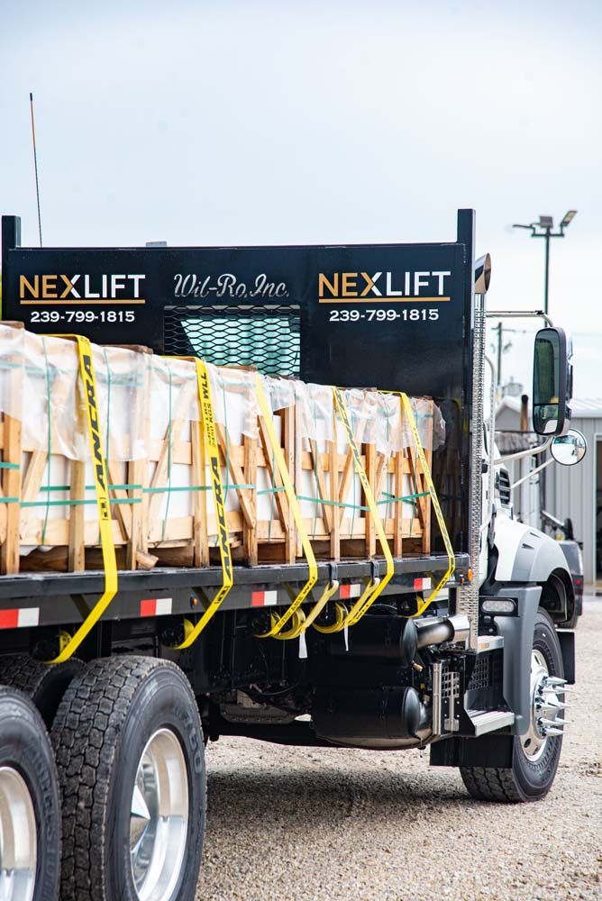 Truck loaded with pallets secured by yellow straps.