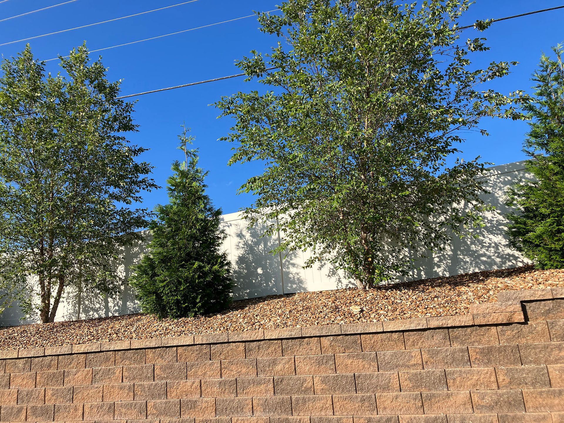 a brick wall with trees and a blue sky in the background