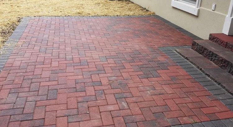 a red and black brick walkway next to a house