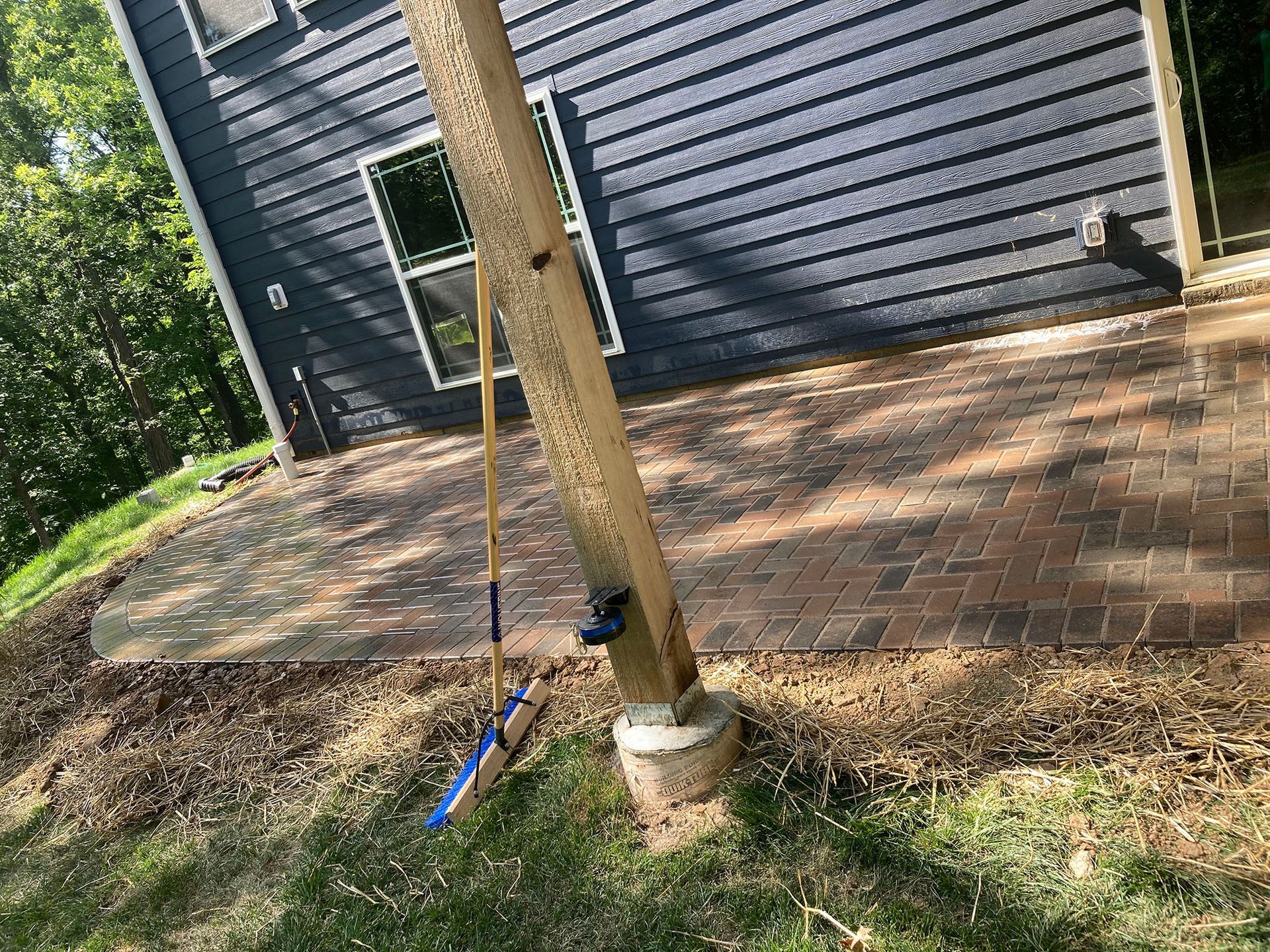 a shovel and rake are sitting on a brick patio in front of a house