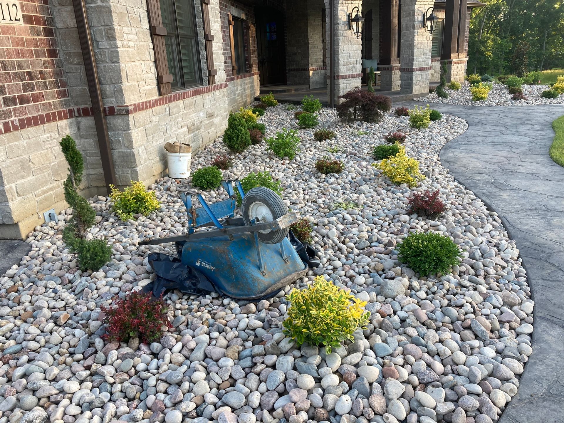 a wheelbarrow is sitting in a pile of rocks in front of a house