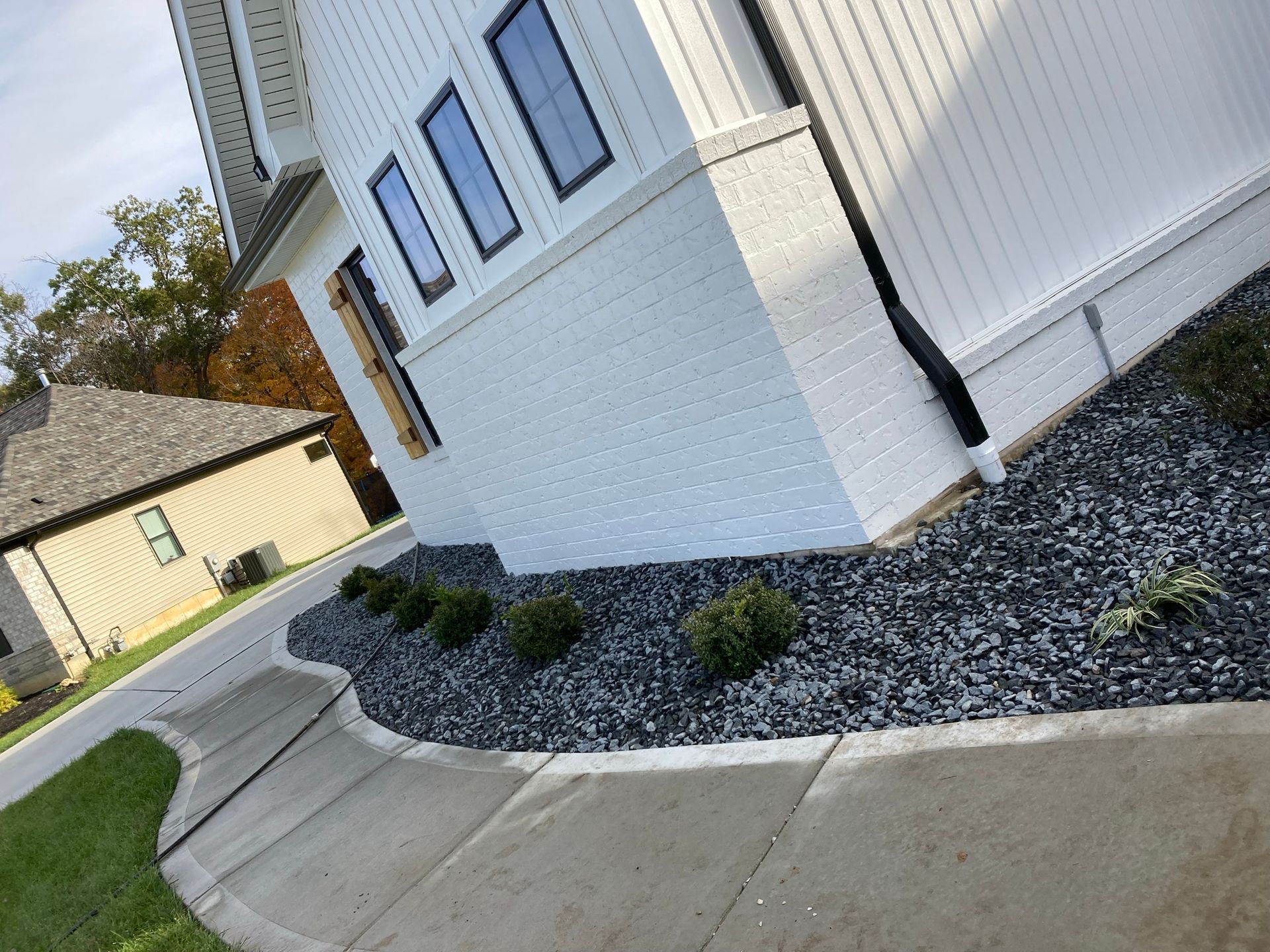 a sidewalk leading to a white house with black gravel in front of it