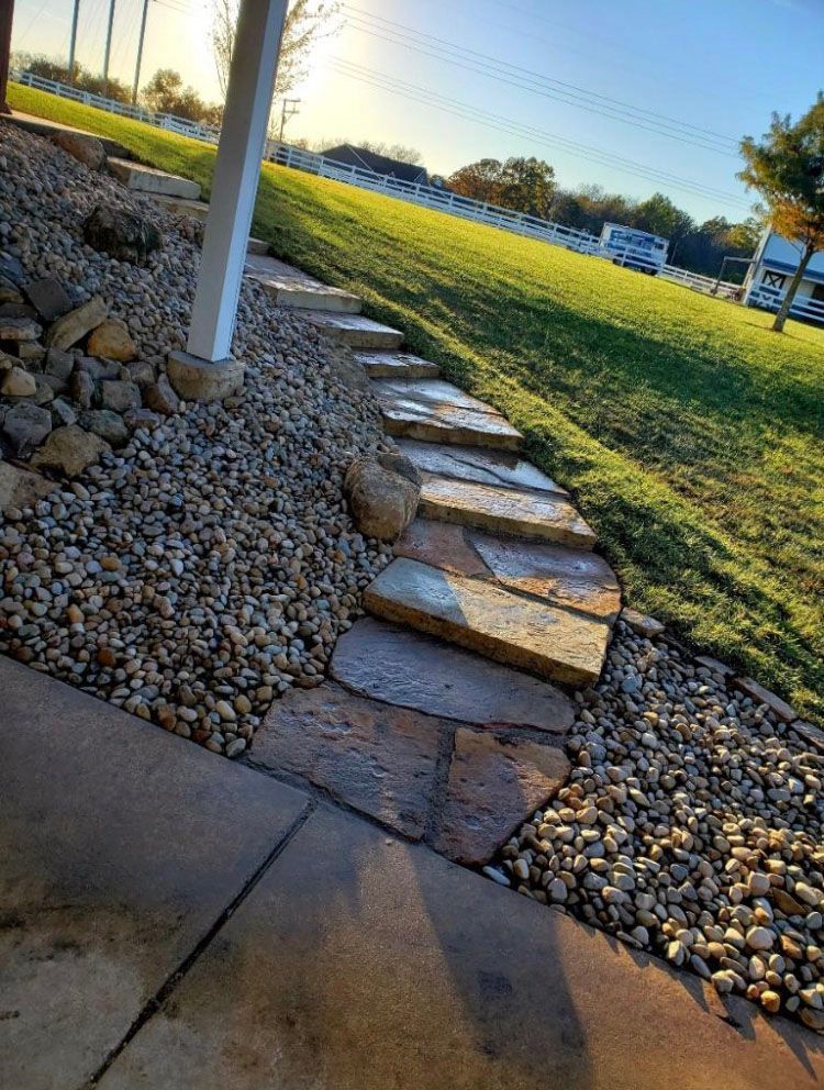 a stone walkway leading to a lush green field