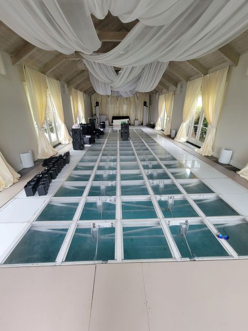 Long banquet hall with draped ceiling and a grid of white-framed floor panels down the center