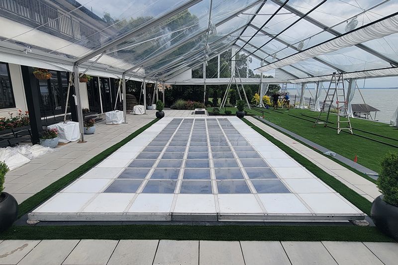 Covered outdoor courtyard with a long glass-paneled walkway and green lawns on both sides