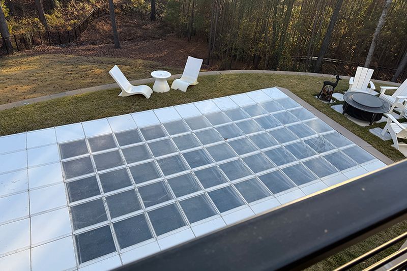 Rooftop view of a skylight with two white lounge chairs and a small table on a grassy deck