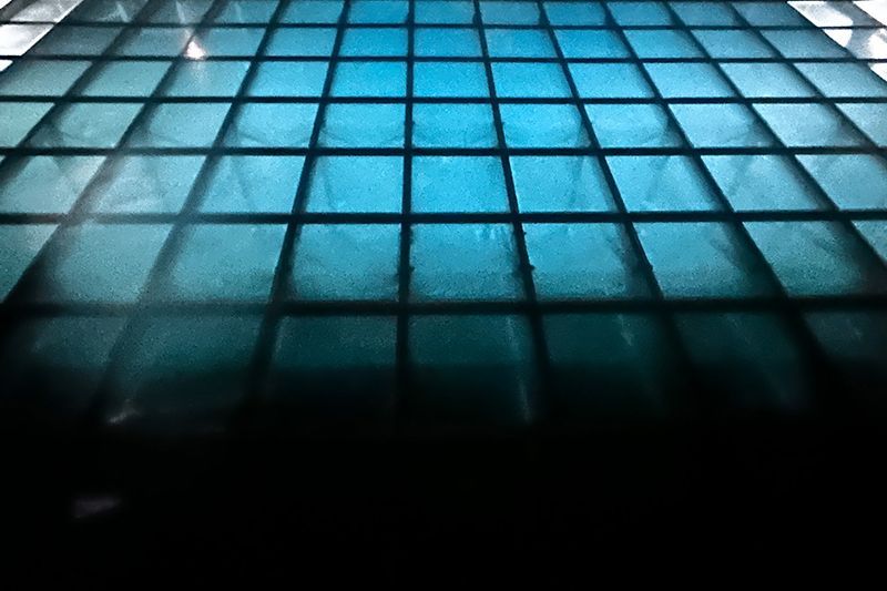 Blue-lit tiled floor with a grid pattern fading into darkness