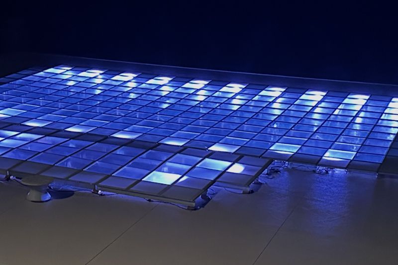 Blue-lit grid of glowing floor tiles in a dark room