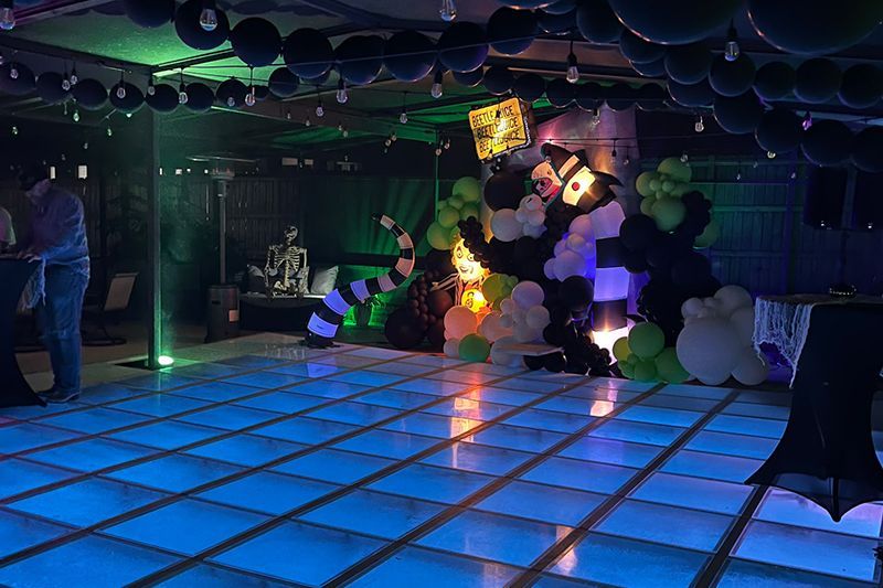 Glowing blue dance floor with balloons, lights, and a panda decoration in a dark party venue