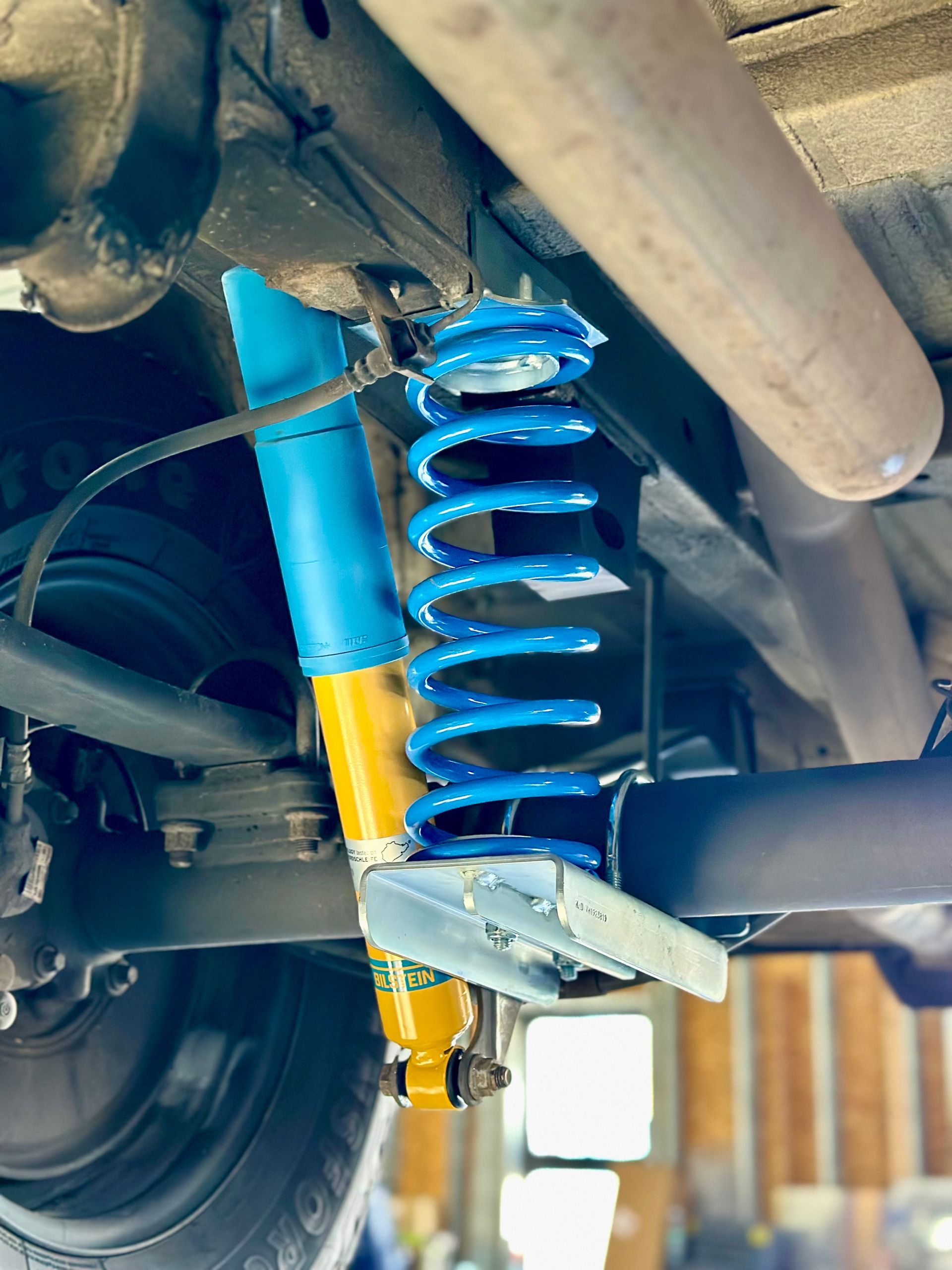 White truck cab in a workshop, chassis visible. A person in the background.