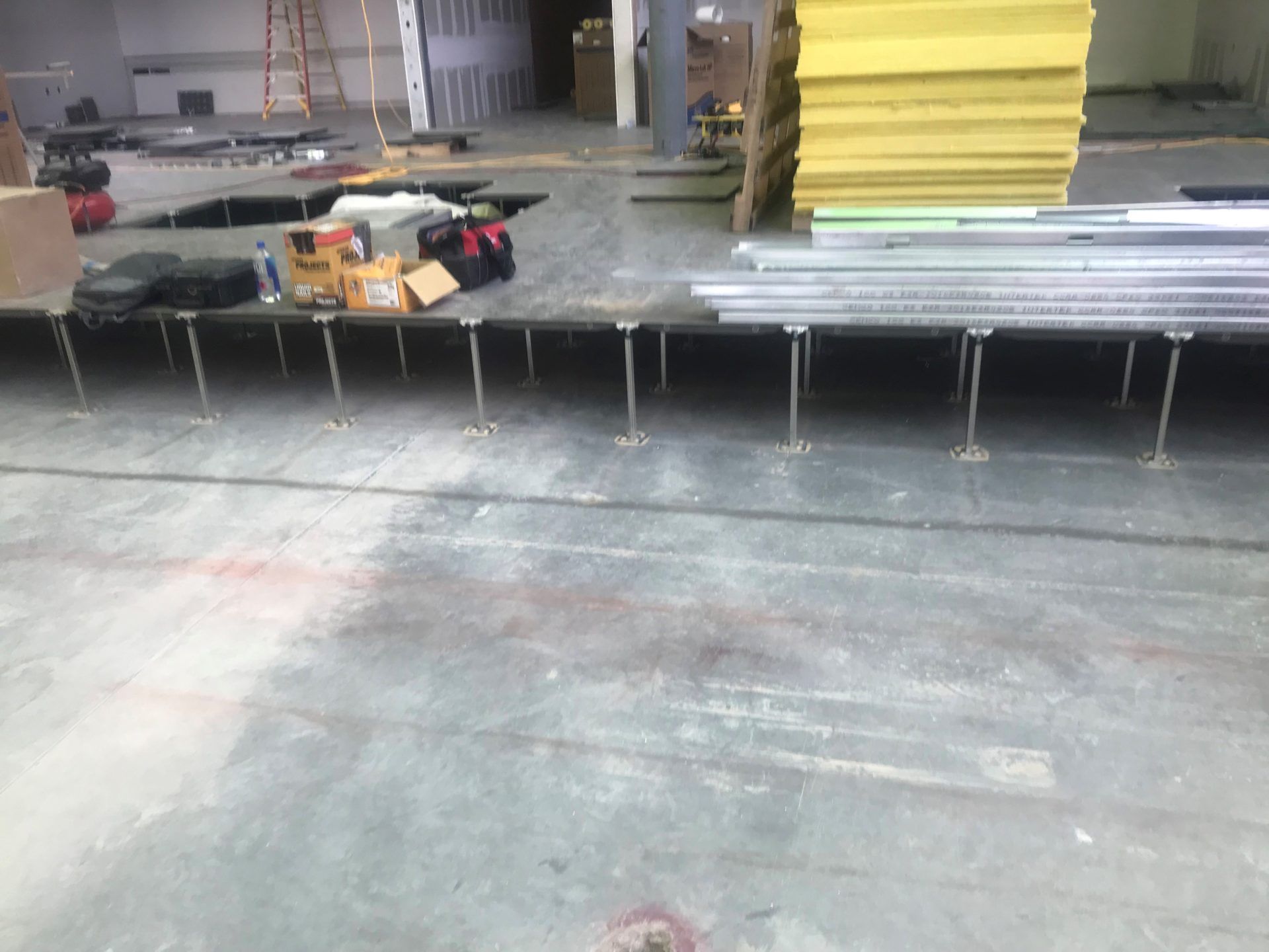 Raised floor system under construction in an industrial space. Metal supports and beams are visible.
