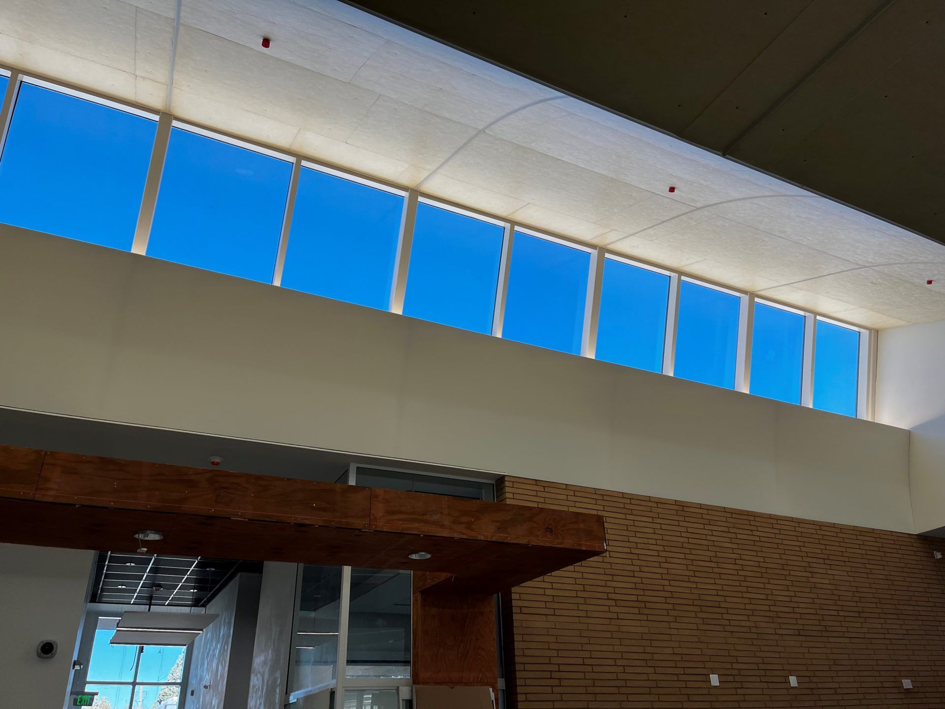 High windows with blue sky visible above a cream-colored wall, interior setting.