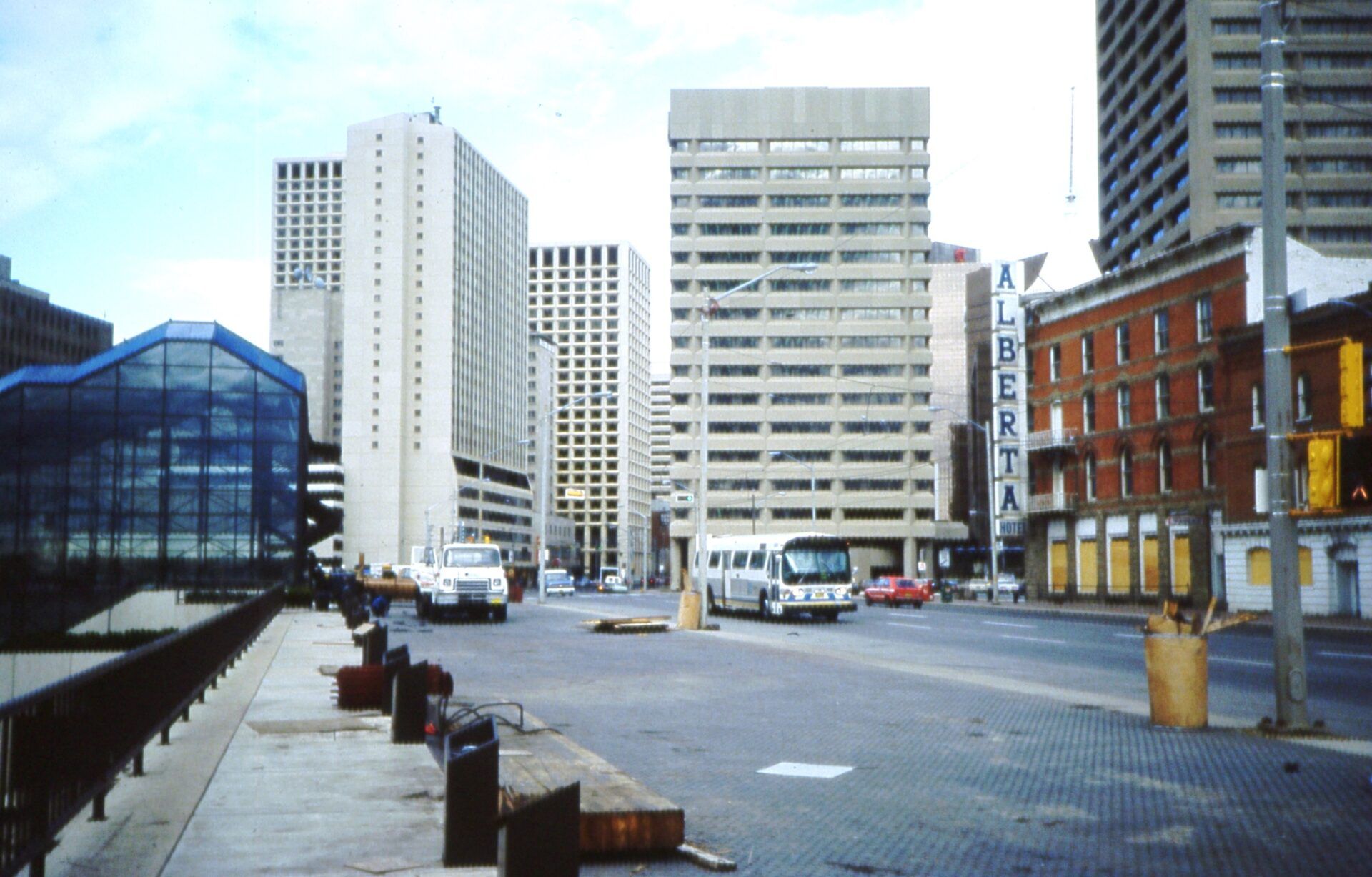 City street with tall buildings, a bus, and a bridge. Weathered brick building on right.