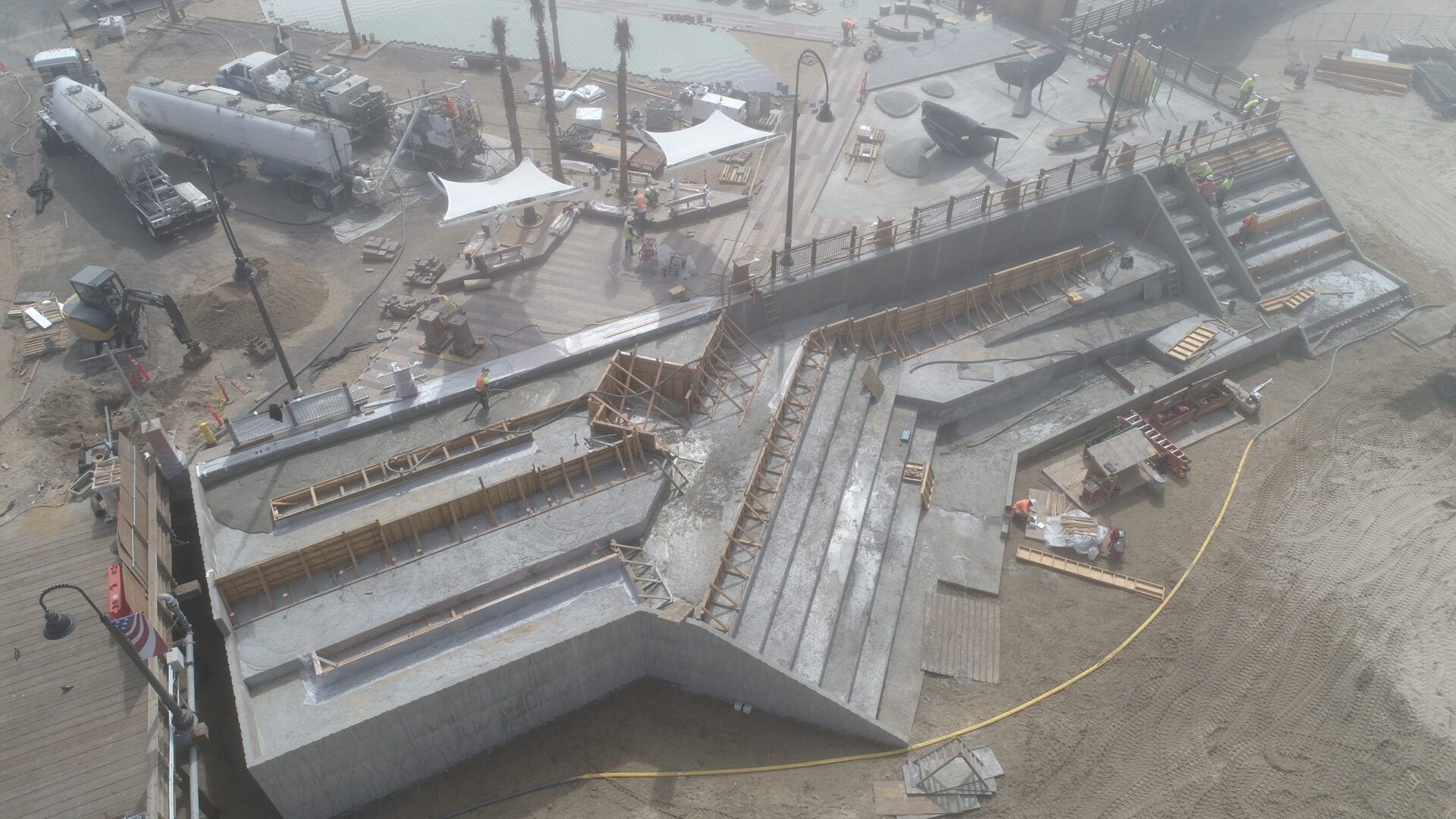 An aerial view of an outdoor construction site showing tiered, gray concrete steps and wooden formwork.