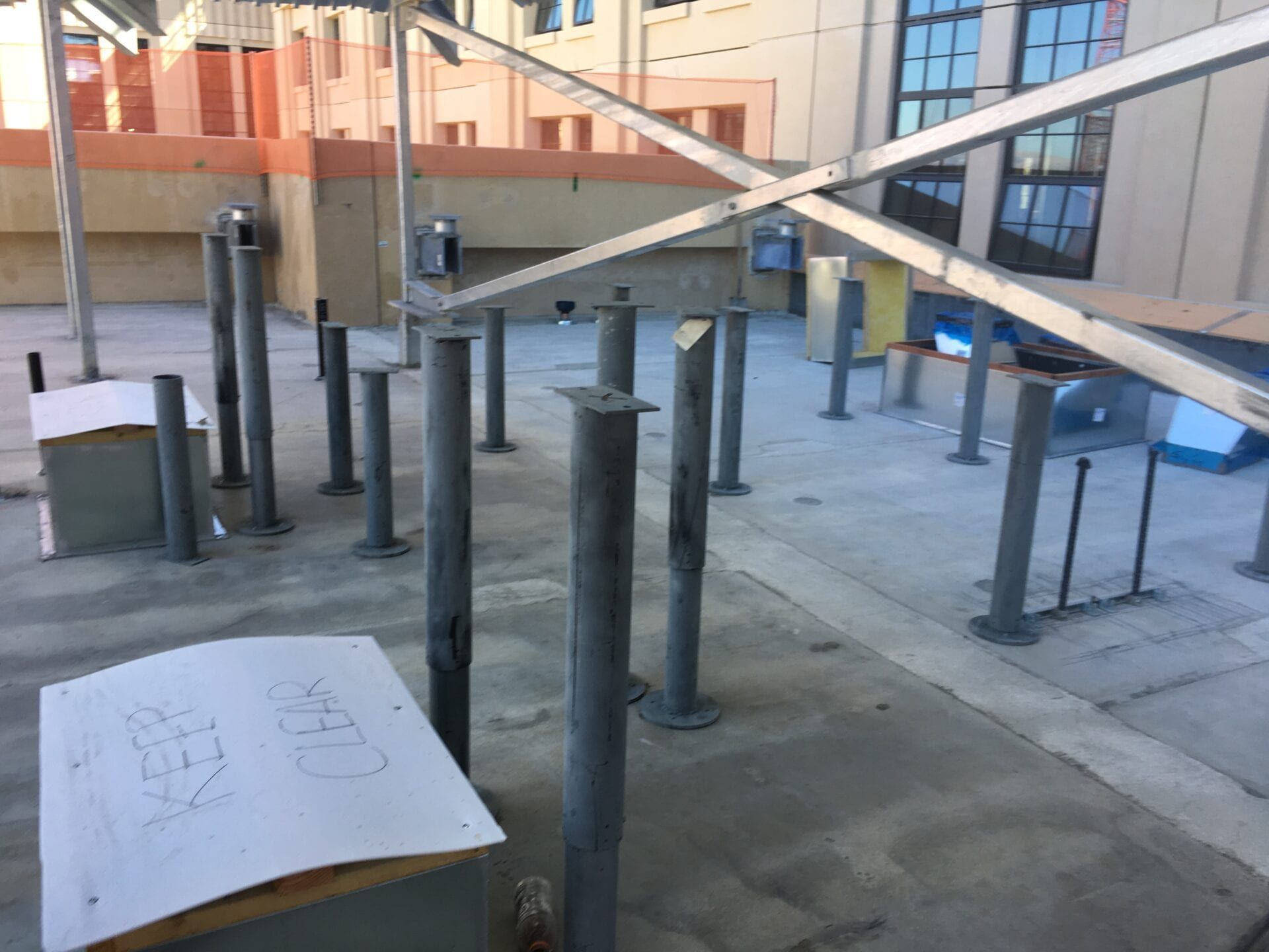 A construction site rooftop with numerous vertical metal support posts and an overhead metal frame structure.