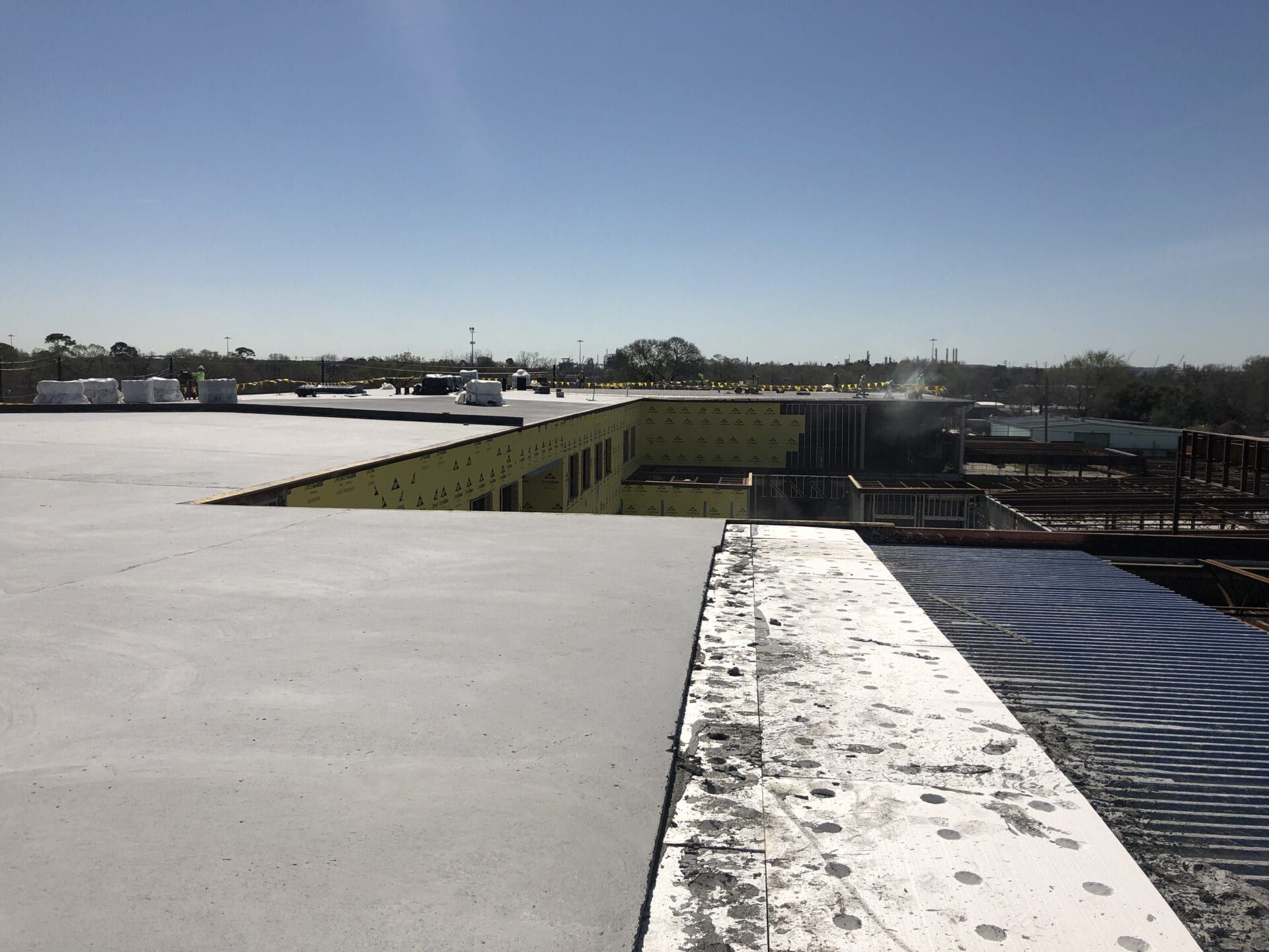 An elevated view of a flat concrete construction site with yellow insulation boards and exposed structural elements.