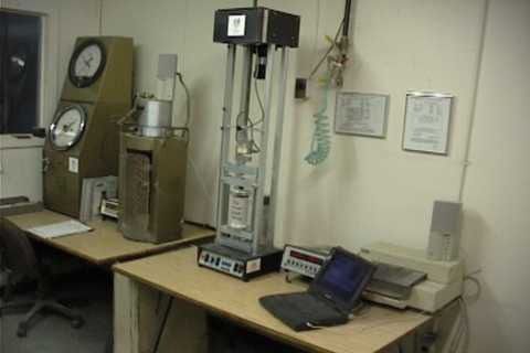 Laboratory testing equipment on a desk with a laptop and gauges.