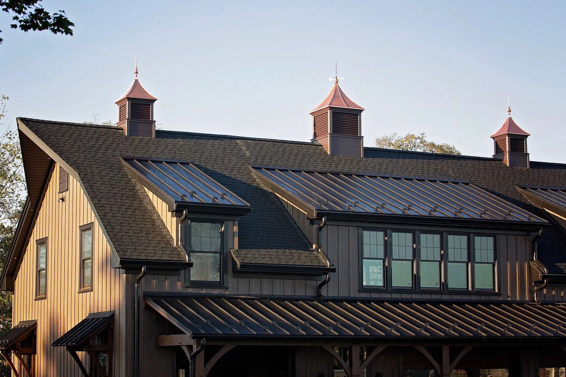Barn with dark roof, three copper-topped cupolas, and wooden siding.