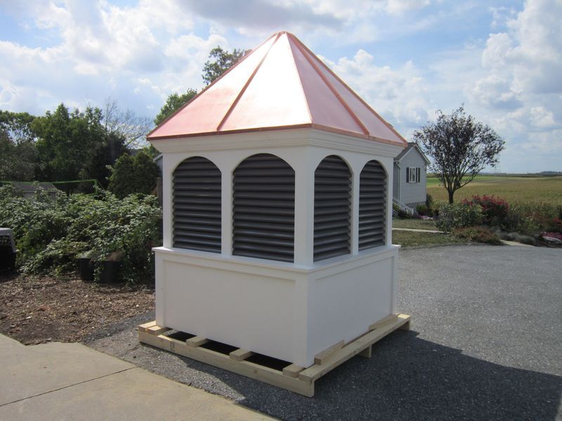 White and copper cupola with arched vents. Resting on wooden pallet outdoors.