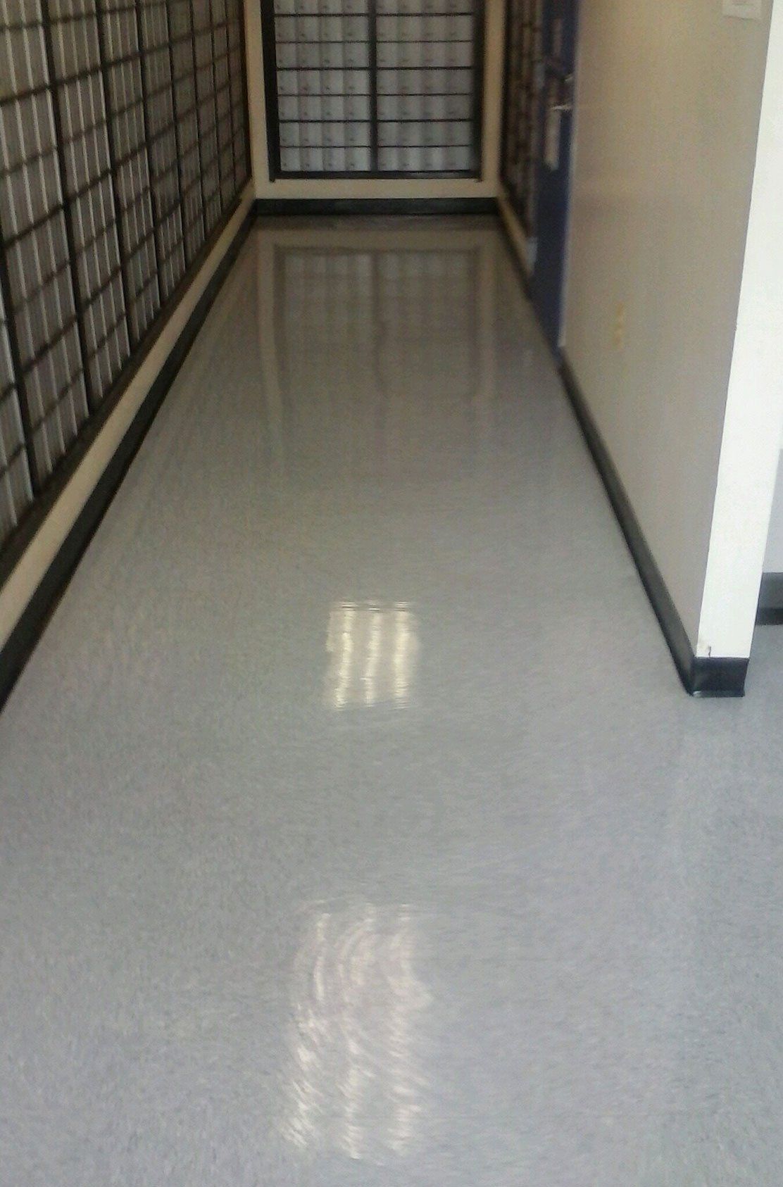 A hallway with a gray floor and a white wall.