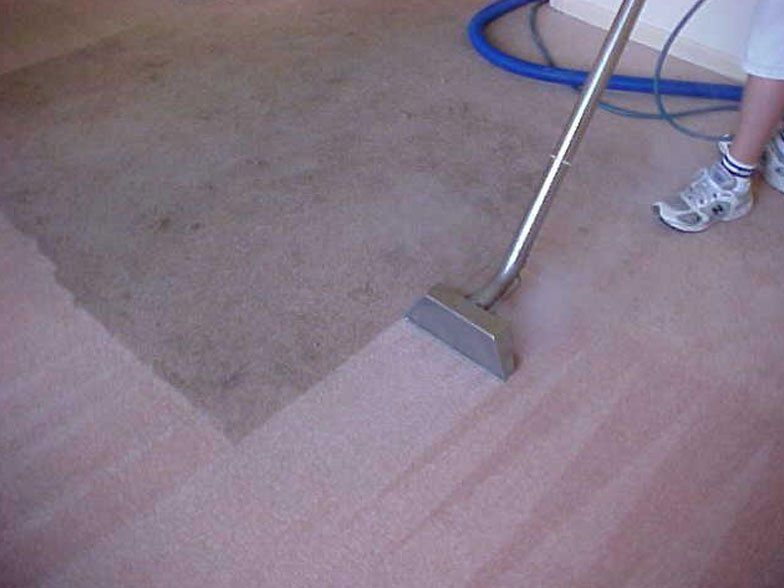 A person is cleaning a carpet with a vacuum cleaner