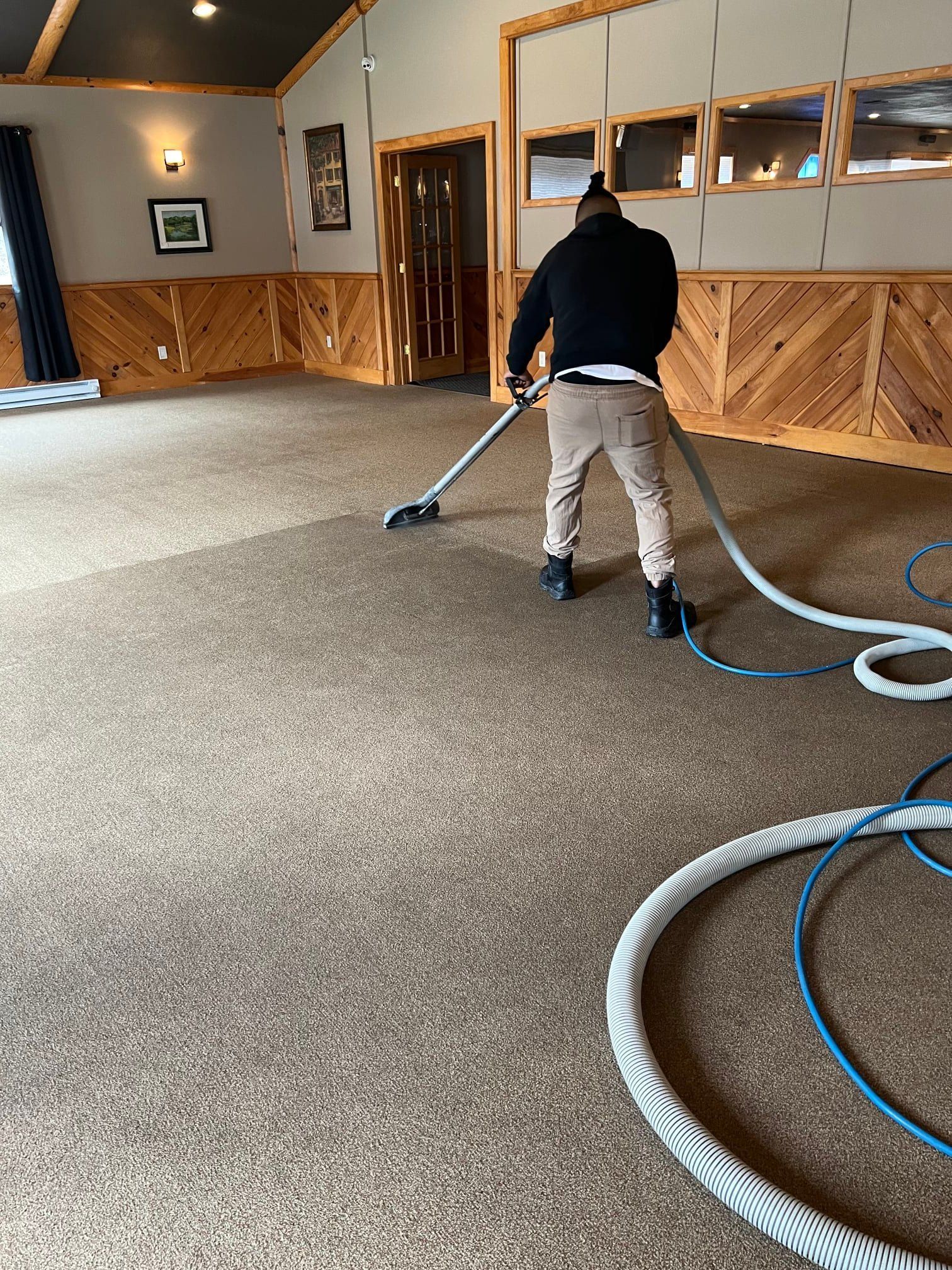 A man is using a vacuum cleaner to clean a carpet in a room.
