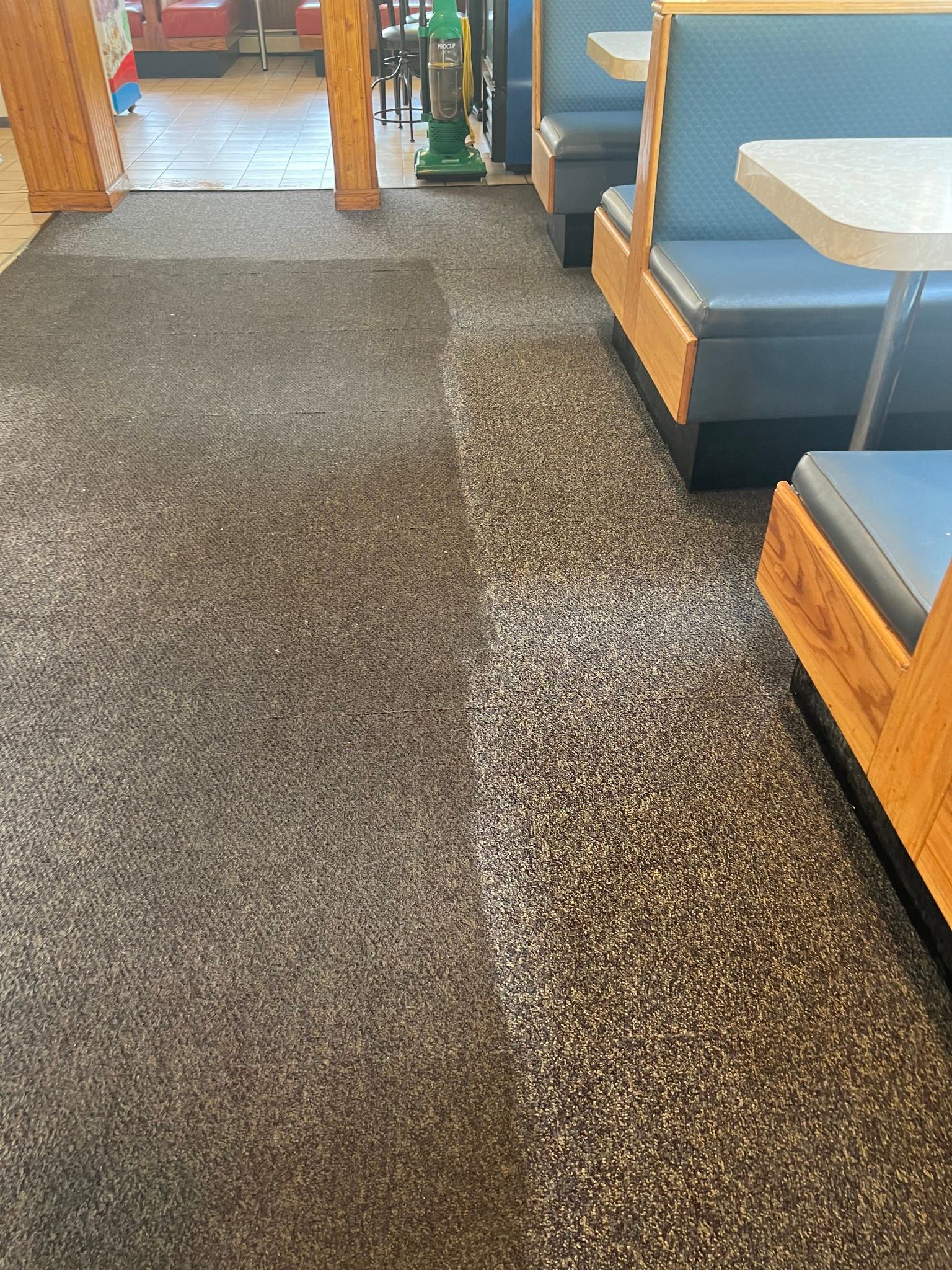A restaurant with tables and benches and a carpeted floor.