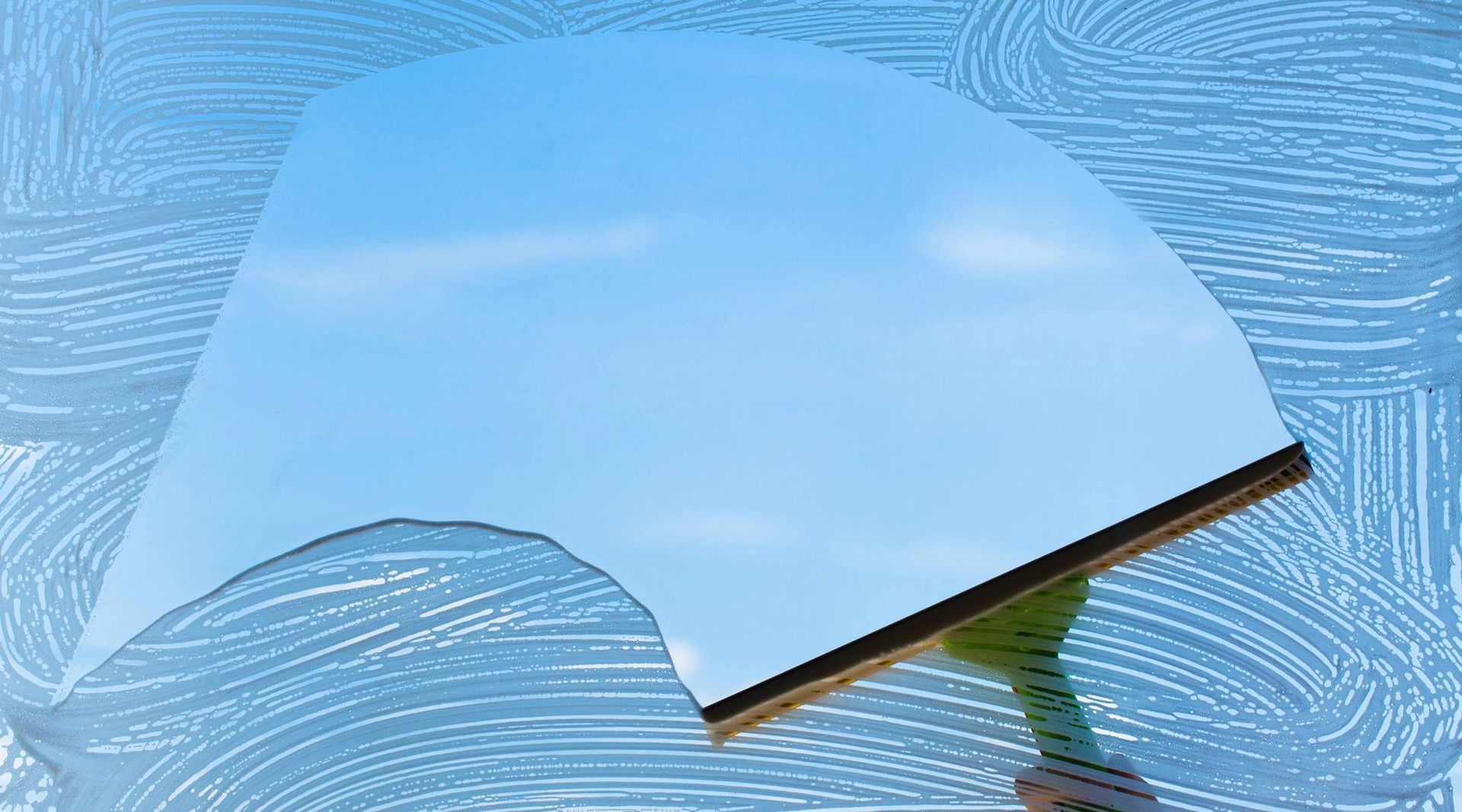 A person is cleaning a window with a squeegee.