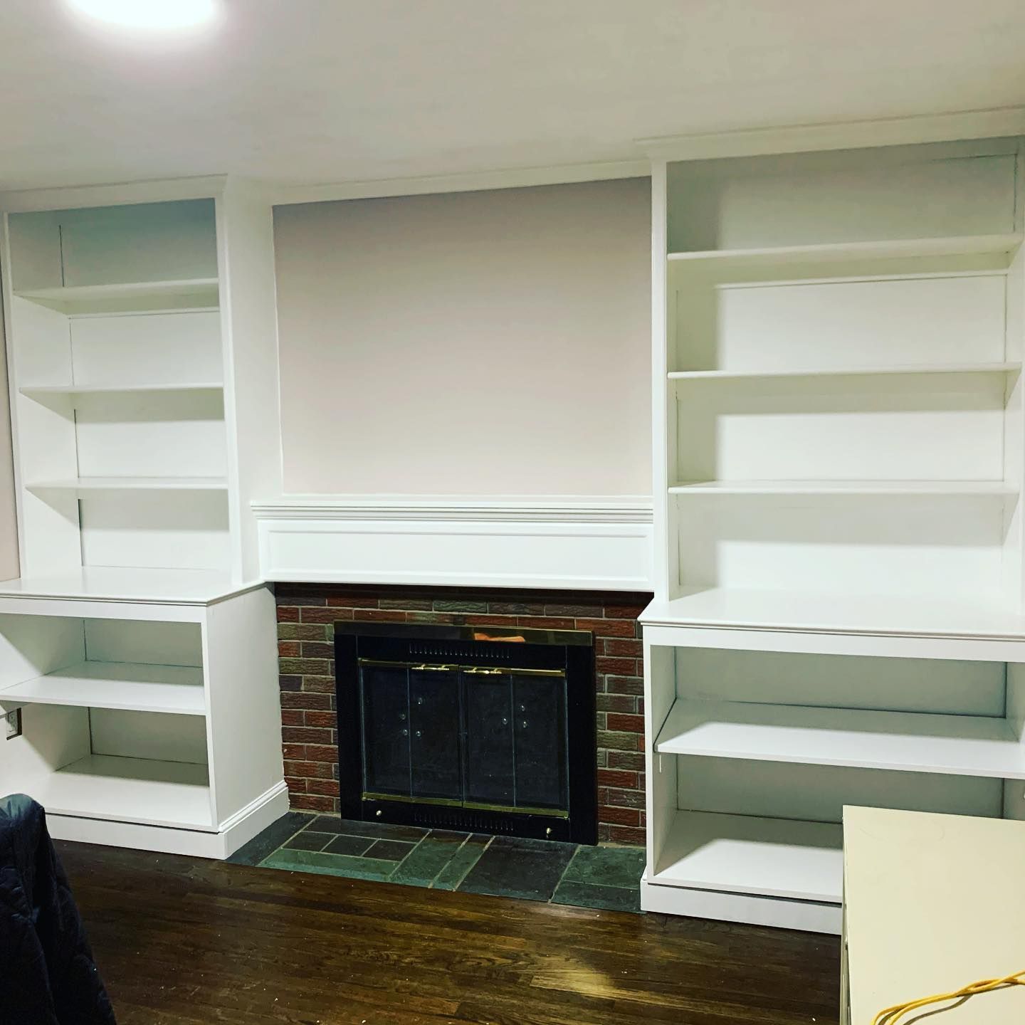 A living room with a fireplace and white shelves