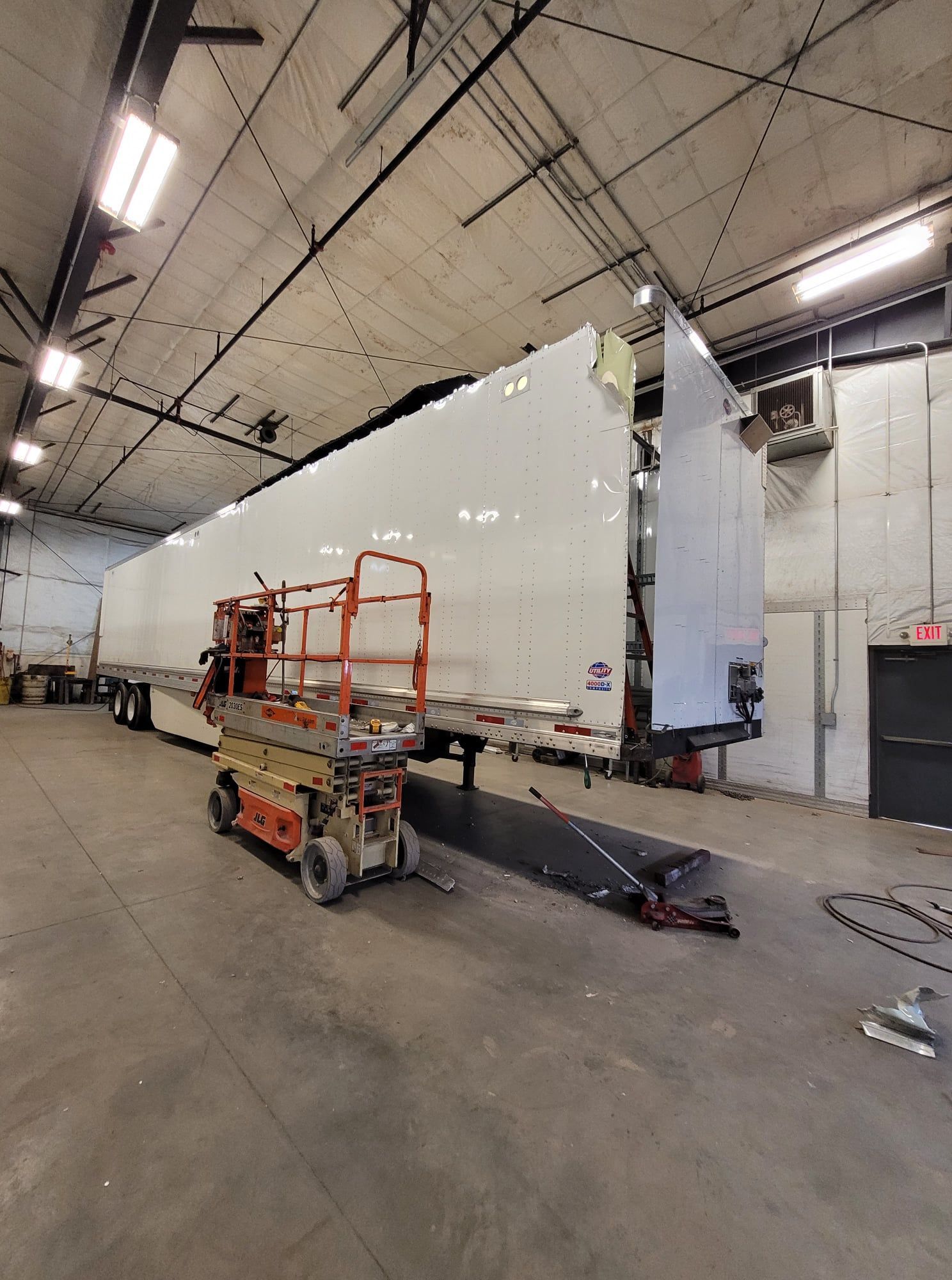 Large white trailer in a warehouse, with an orange lift and ramp in the foreground