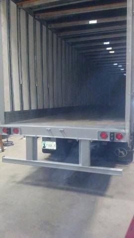 Open box truck trailer interior with empty cargo space and rear lights in a warehouse loading area
