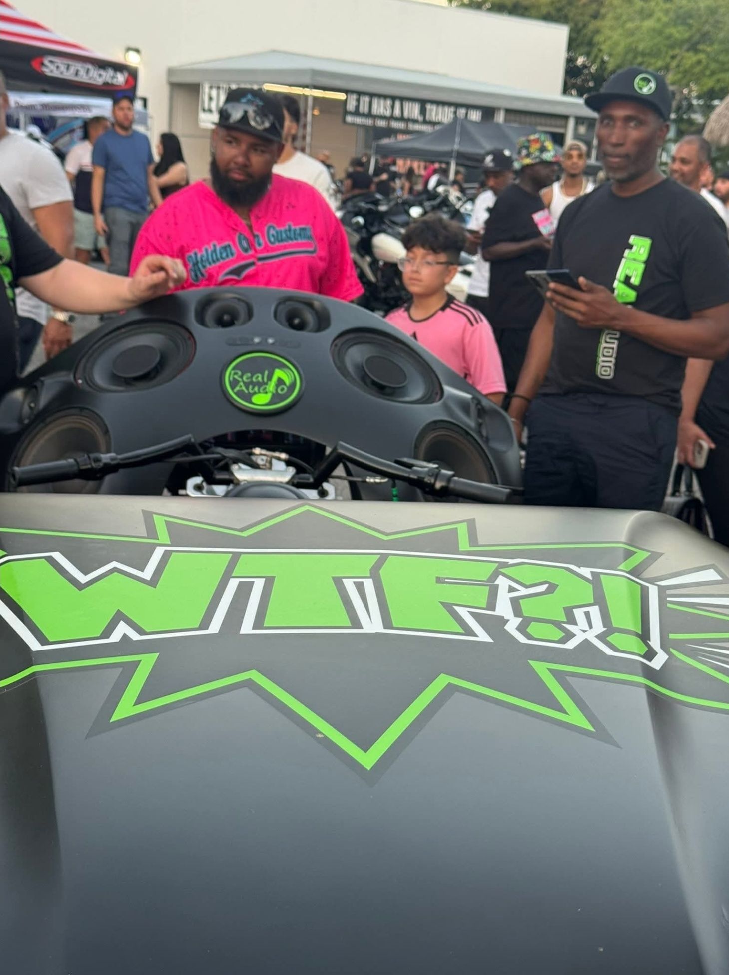 A man in a pink shirt is standing next to a car with the word wired on it
