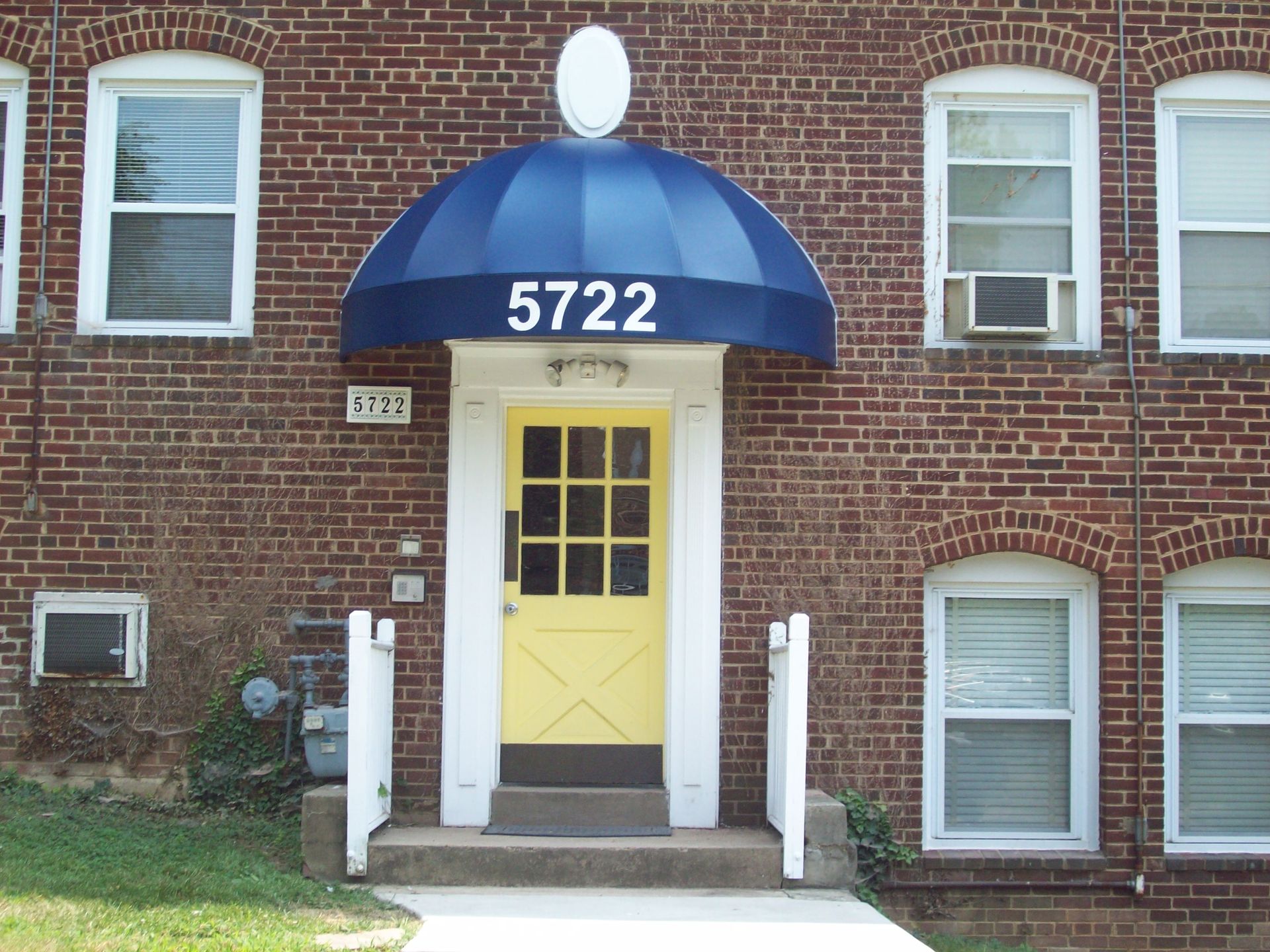 A brick building with a blue awning over the door