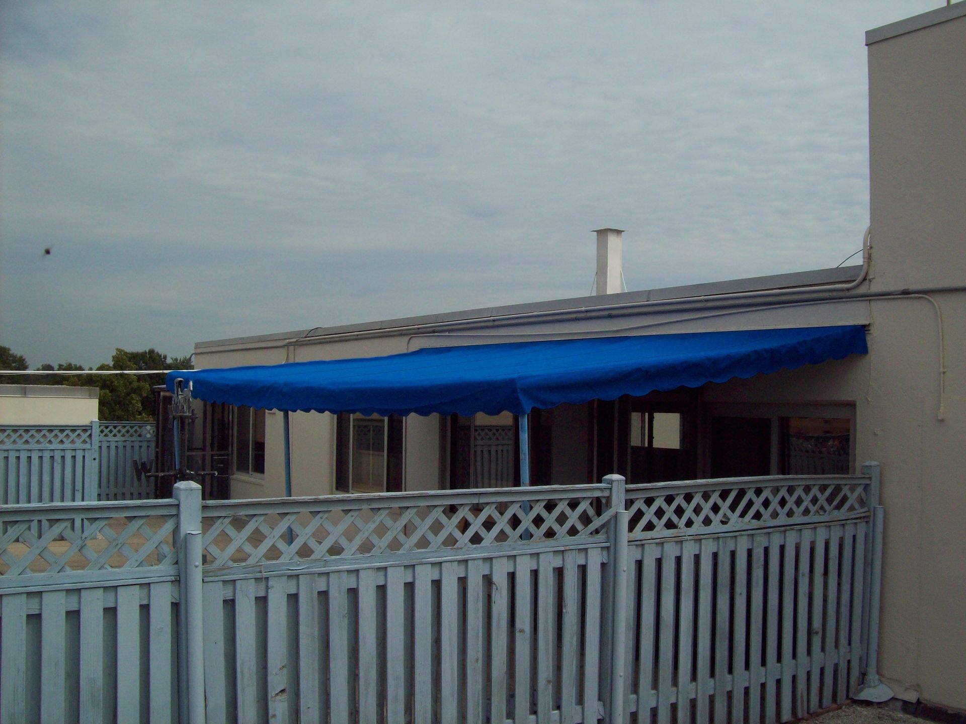 A house with a blue awning and a white picket fence