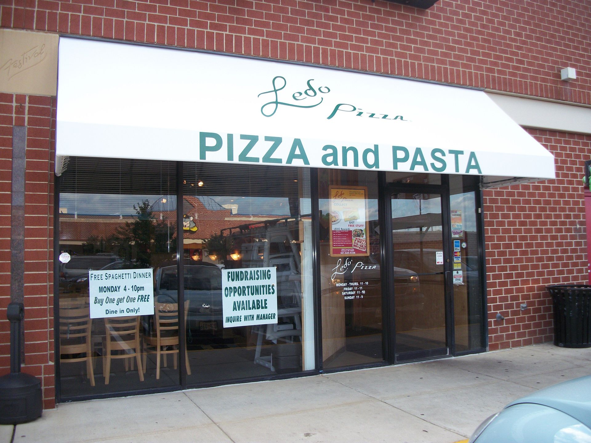 A brick building with a white awning that says Pizza and Pasta