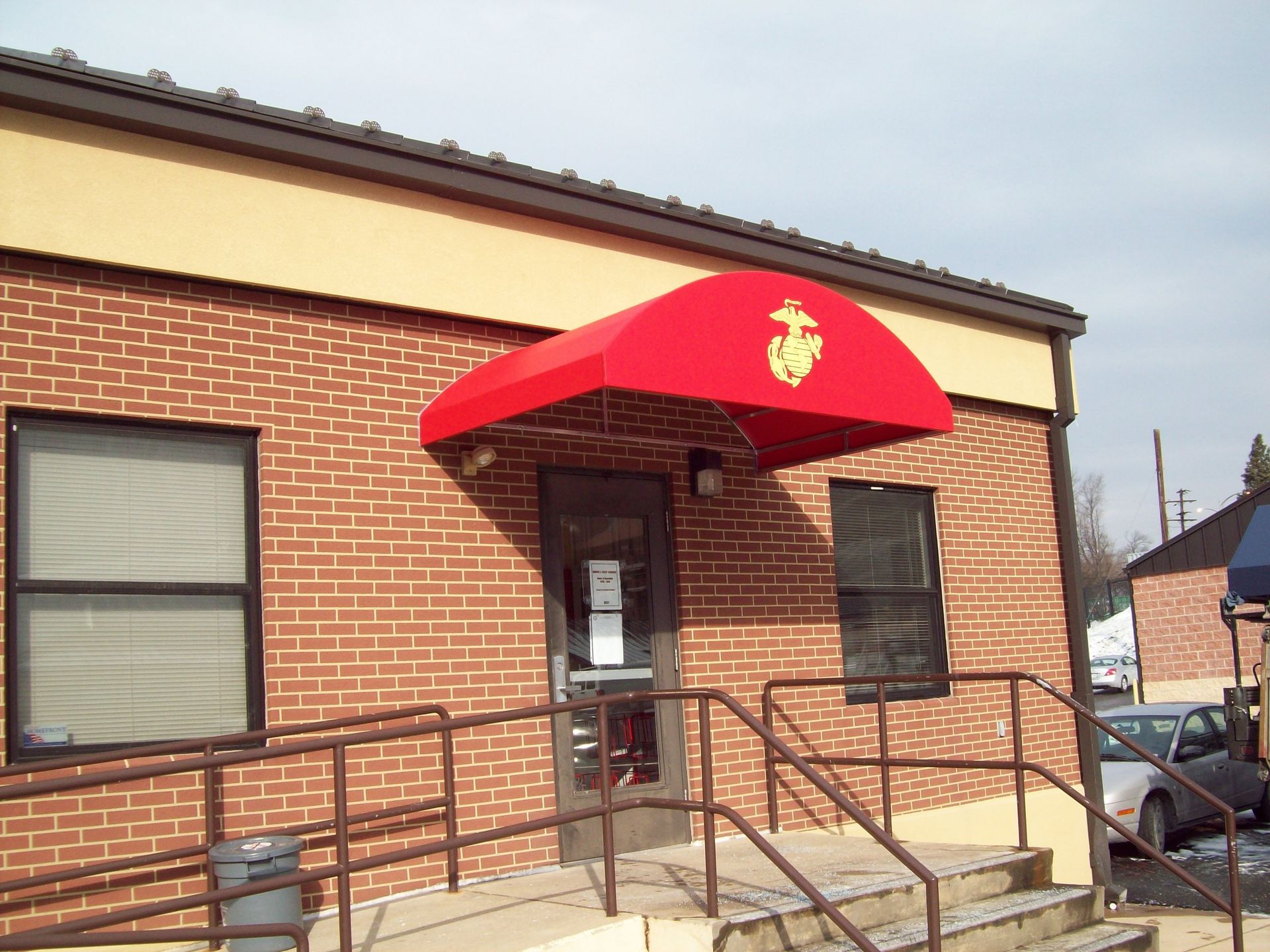 A brick building with a red awning over the door