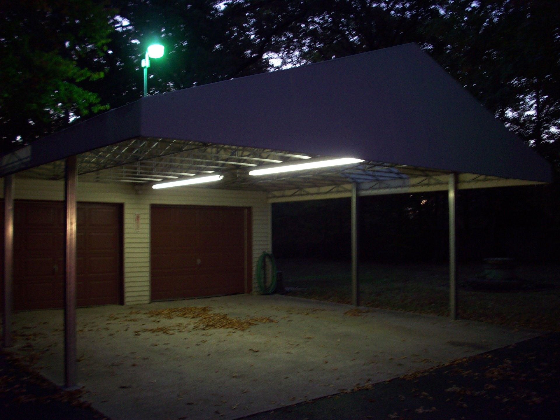 A carport is lit up at night with a green light