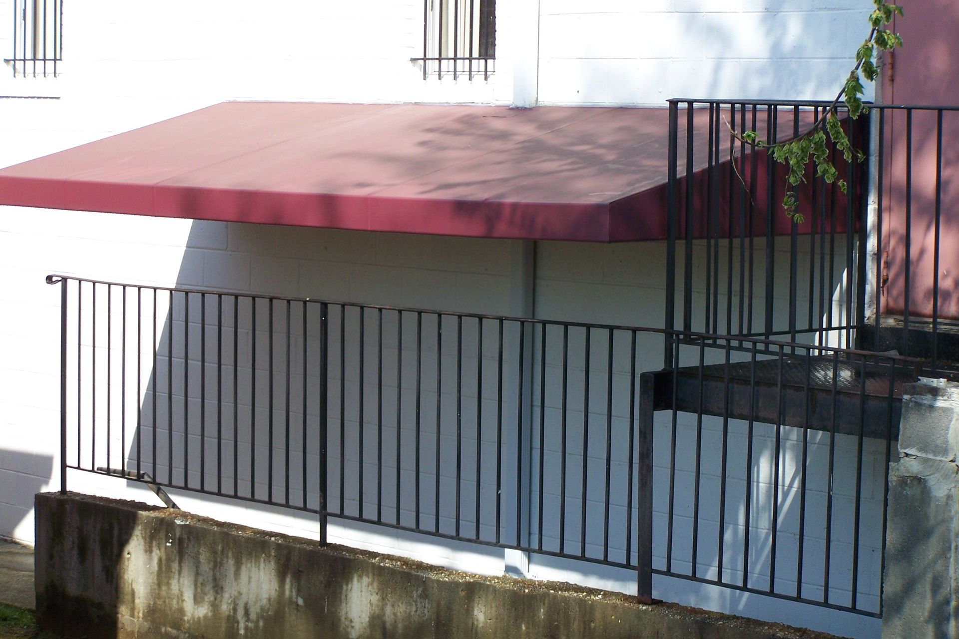 A balcony with a red awning and a black railing