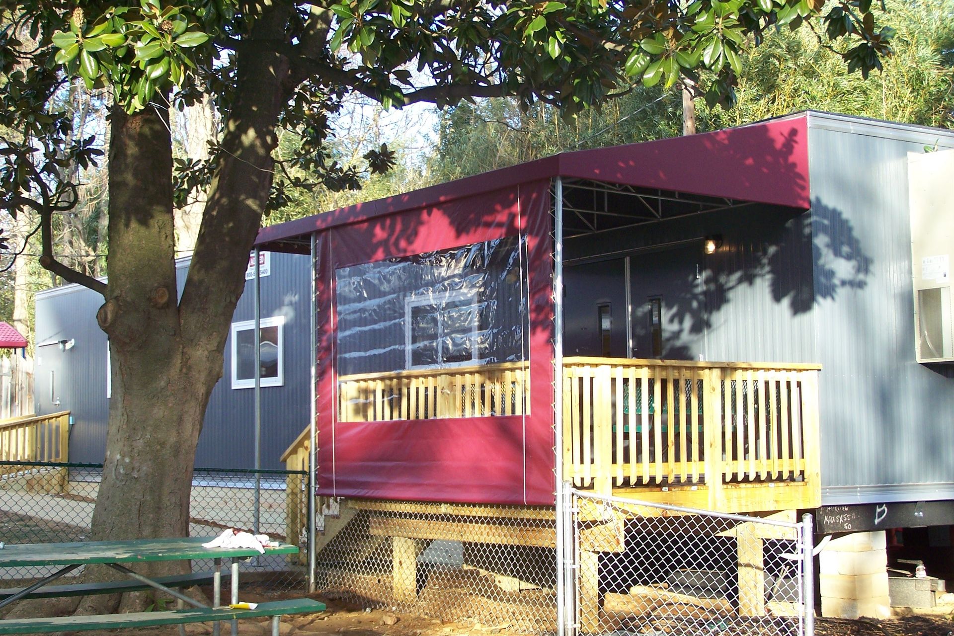 A small house with a red awning and a picnic table in front of it