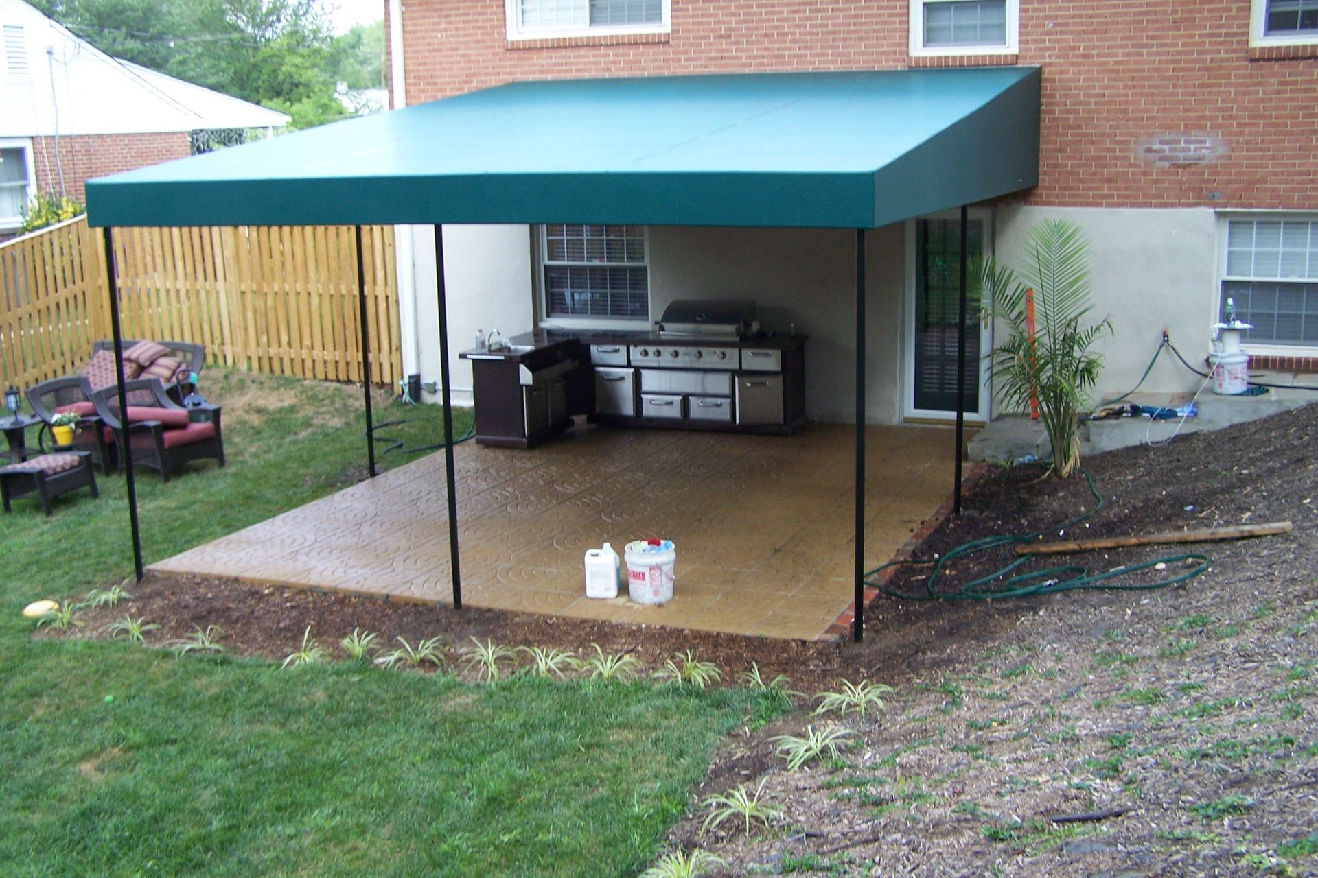 A backyard with a green awning over a patio