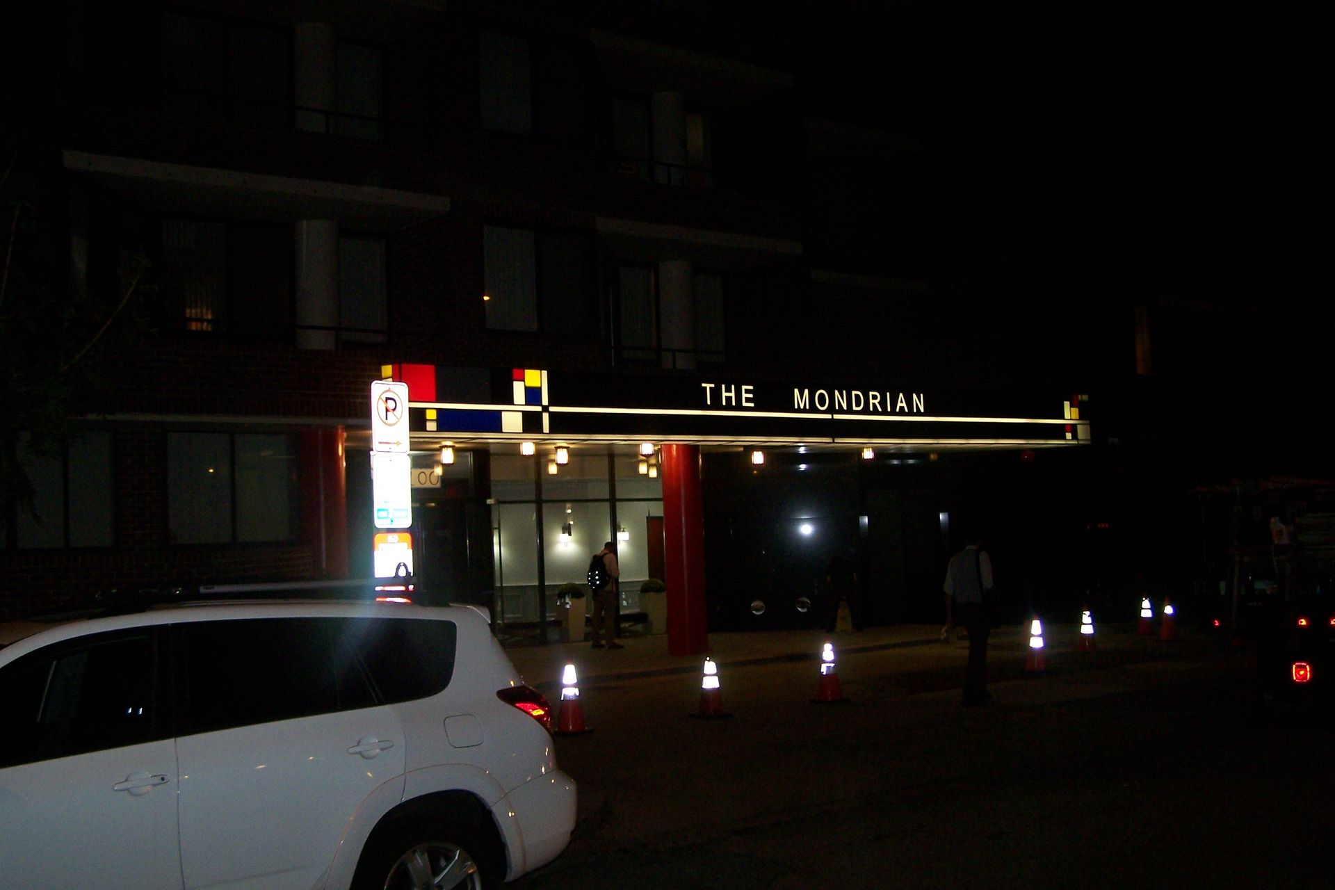 A white car is parked in front of a building that says the mosquito