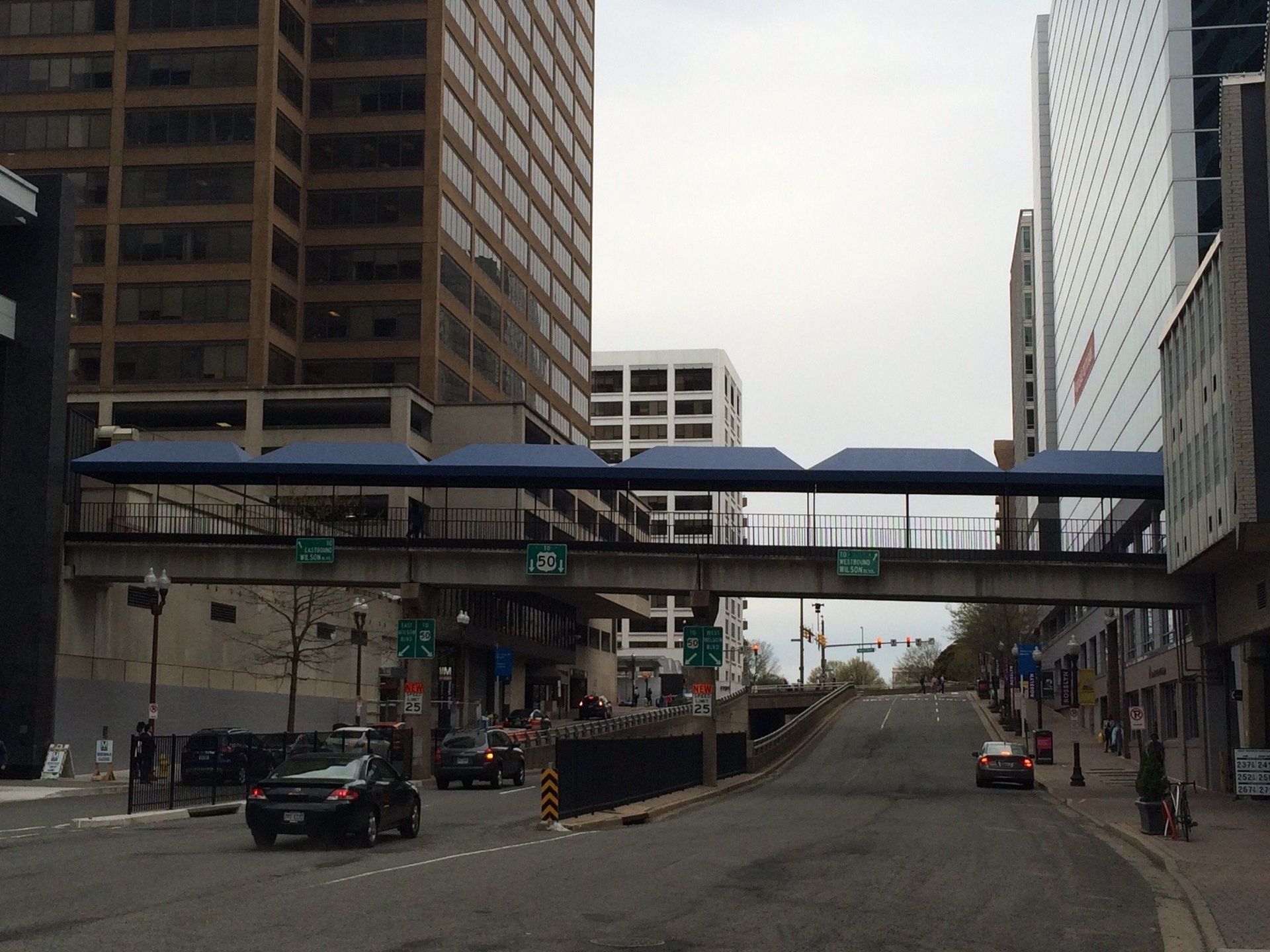 A car is driving under a bridge with a sign that says no left turns